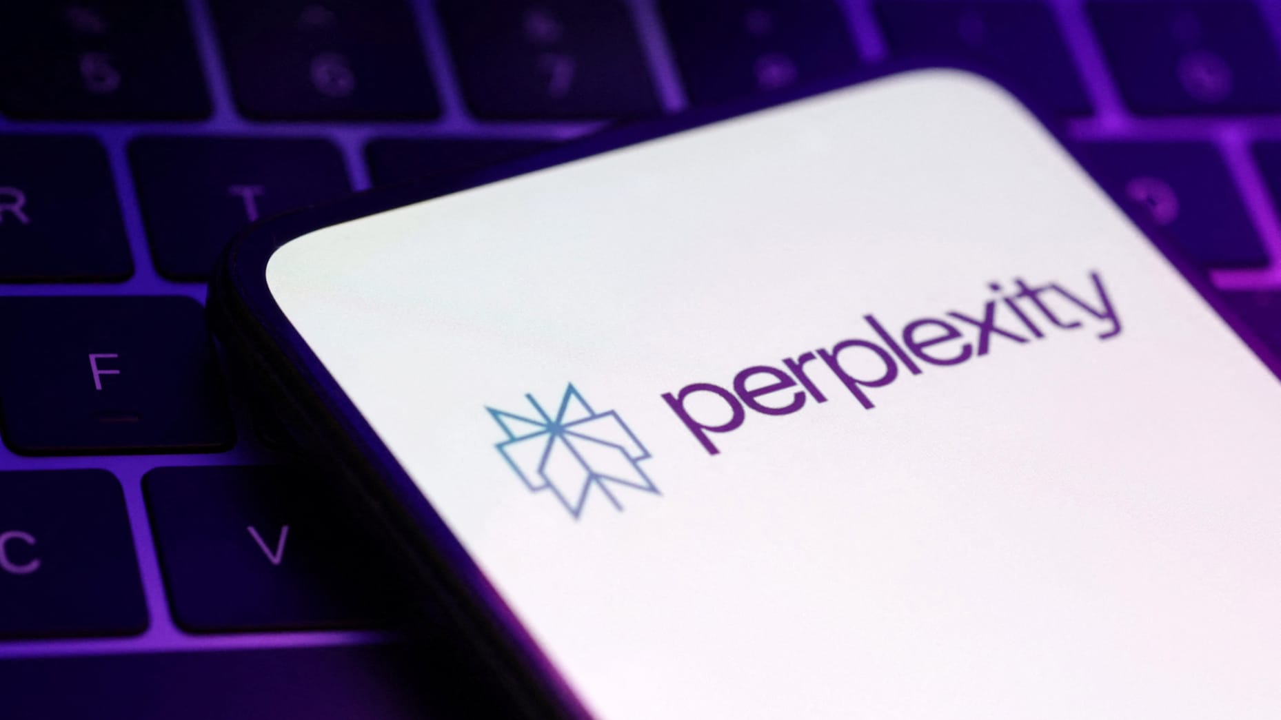 Alt: Perplexity AI logo is displayed on a smartphone screen, with a purple-lit keyboard in the background, highlighting the company's branding.