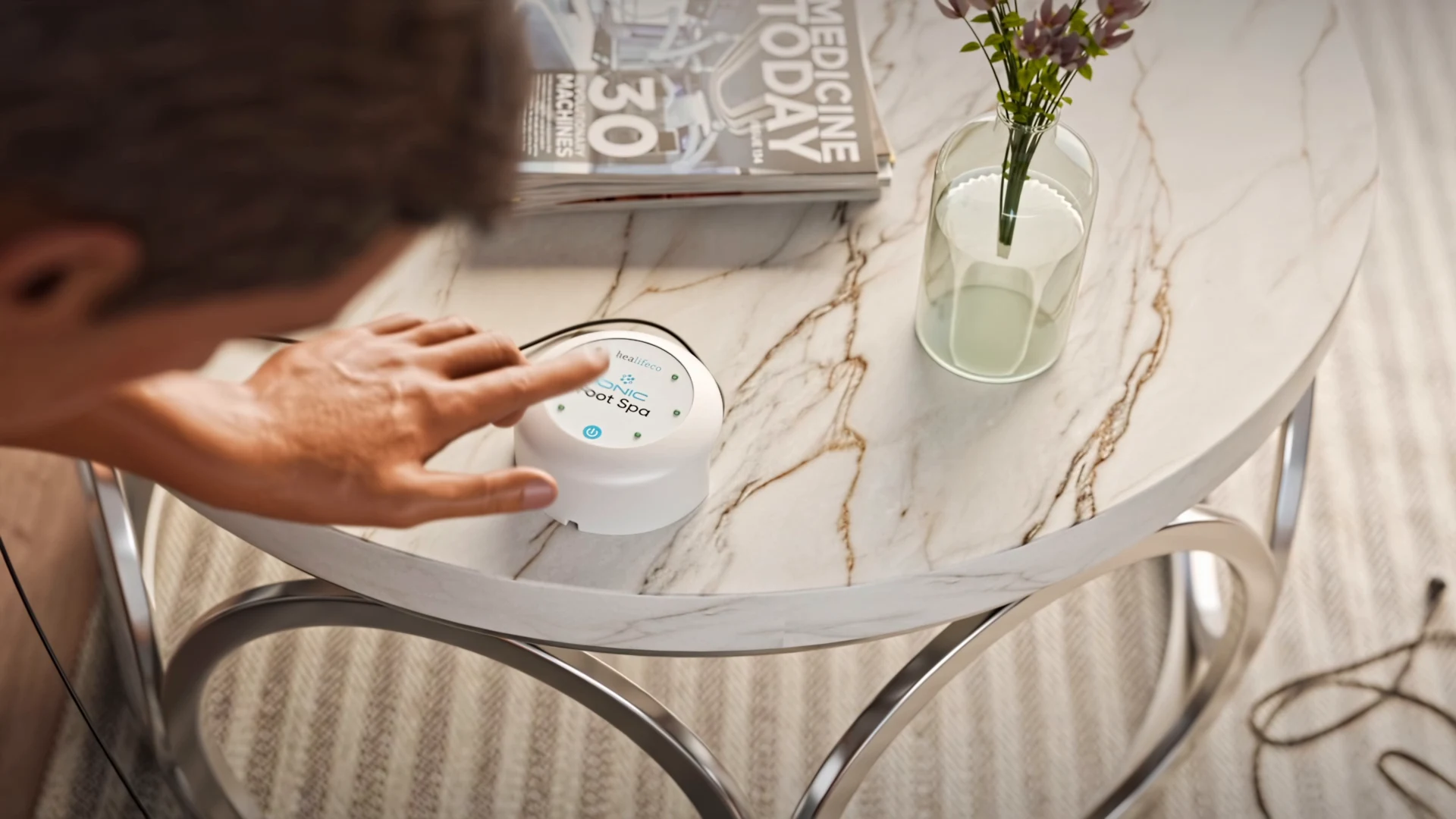 Hand operating the foot-spa controller on a side table