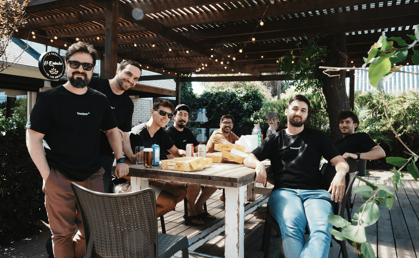Treeview team gathered for an outdoor lunch, wearing branded black t-shirts and smiling at the camera