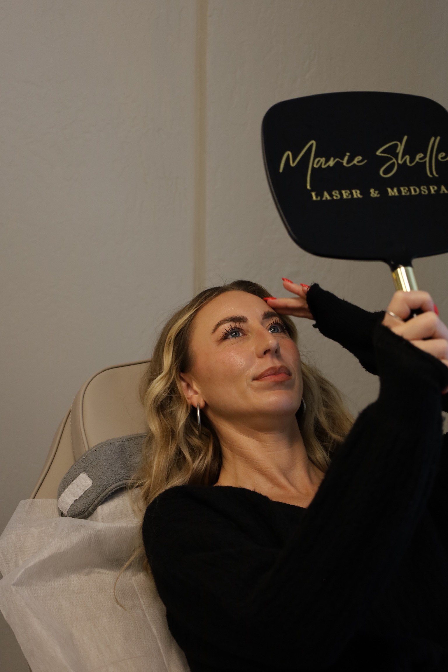 Marie Shelley Laser and Medspa Patient Holding a mirror checking her face