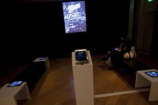 stands with iPads and a presentation of an image projected on the wall