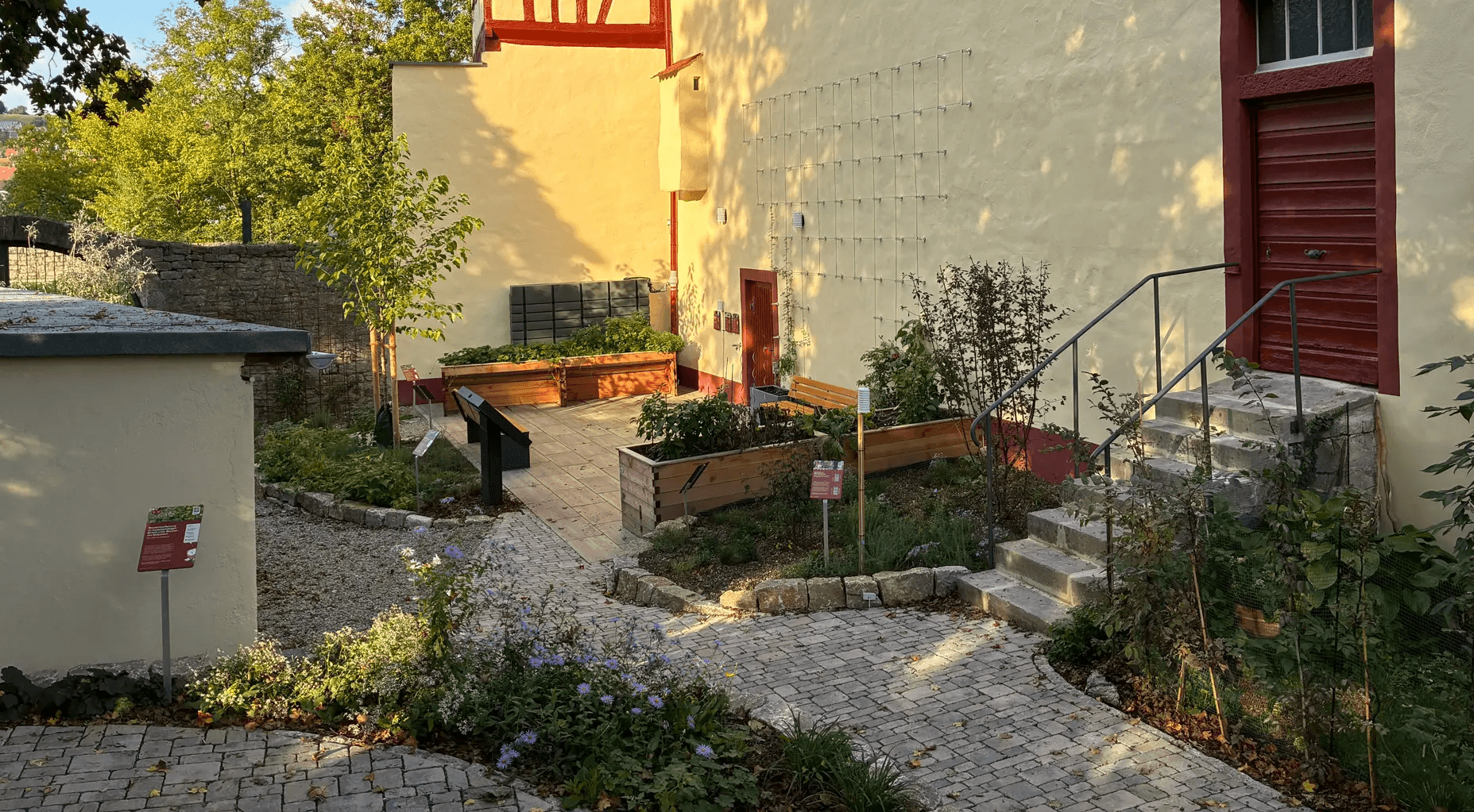 Mitmachgarten in Ochsenfurt, mit Sandstein gepflasterter Weg an einem sonnigen Tag.