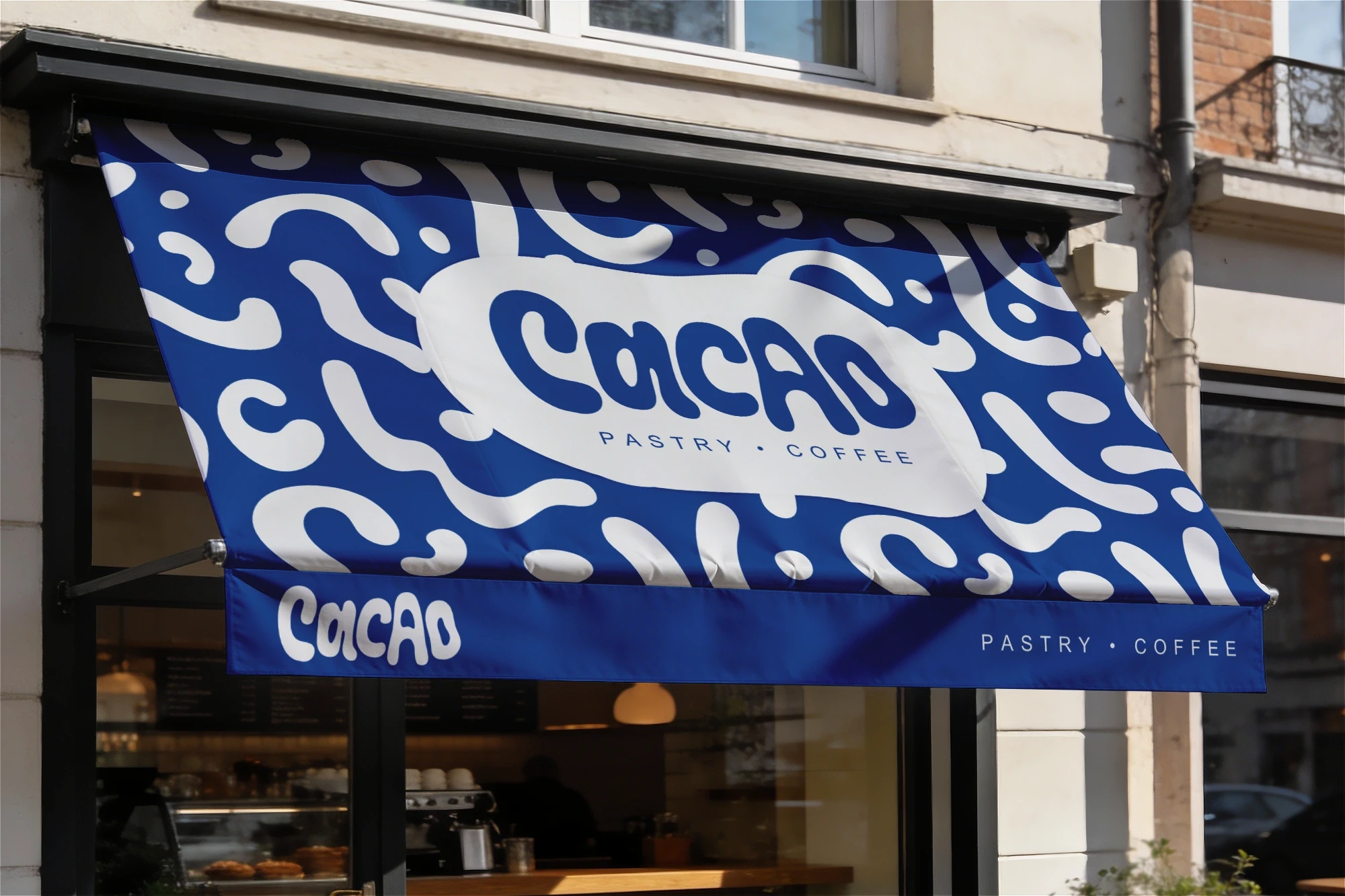 A storefront awning featuring the Cacao pastry shop logo and brand pattern, designed by Studio Liminal.