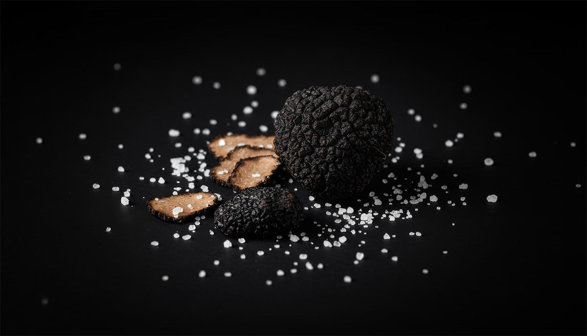 Truffles pieces on a black background with salt crystals
