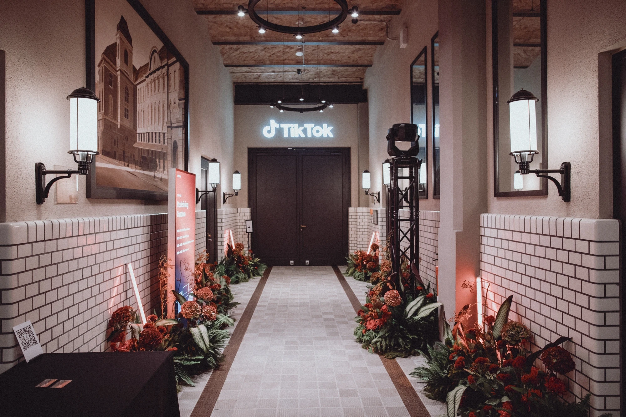 Brick-lined corridor with lanterns, red flower arrangements and glowing TikTok logo above the door.