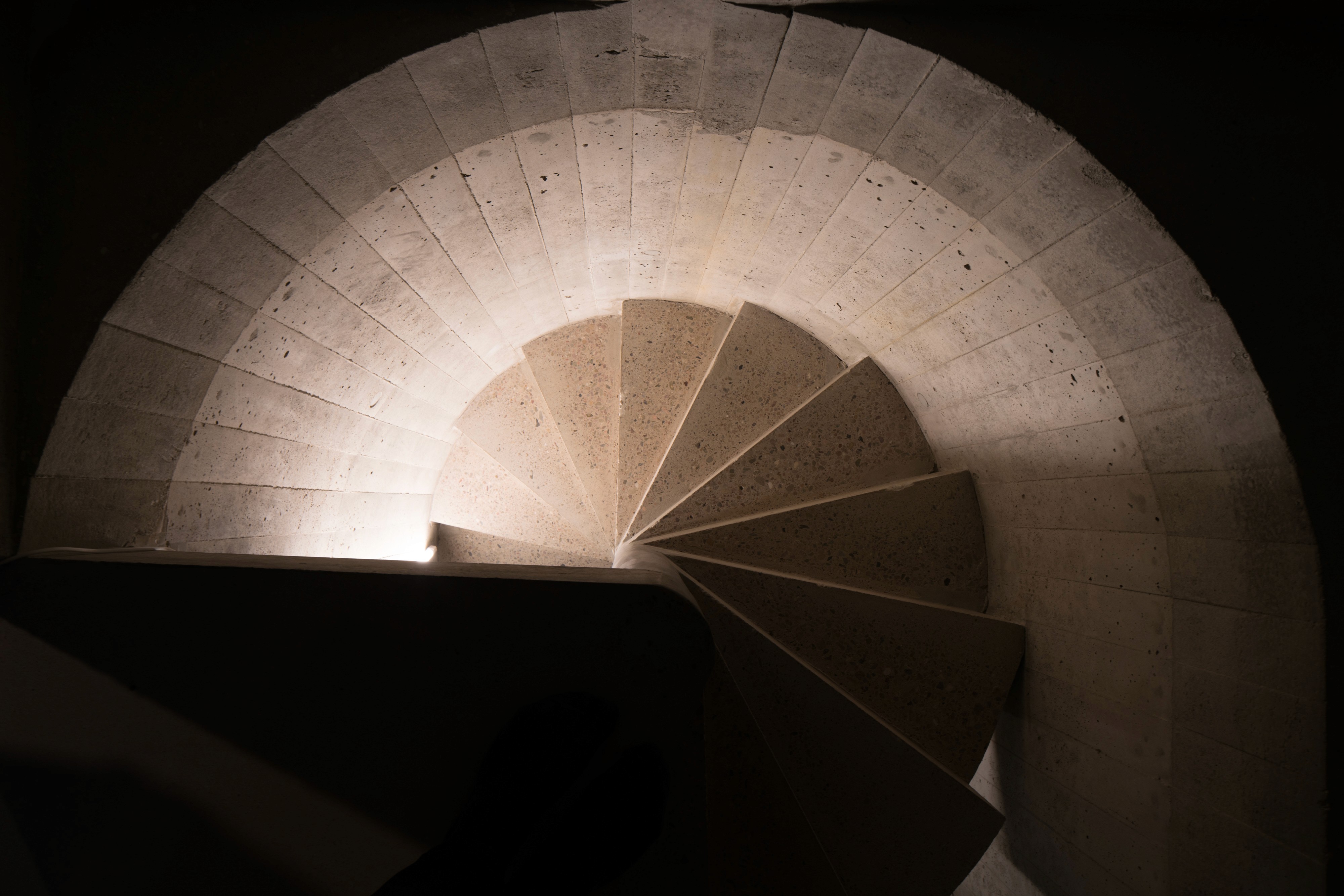 Modern red brick apartment or office building viewed from below against a blue sky, showcasing its geometric architecture with evenly spaced windows and balconies.