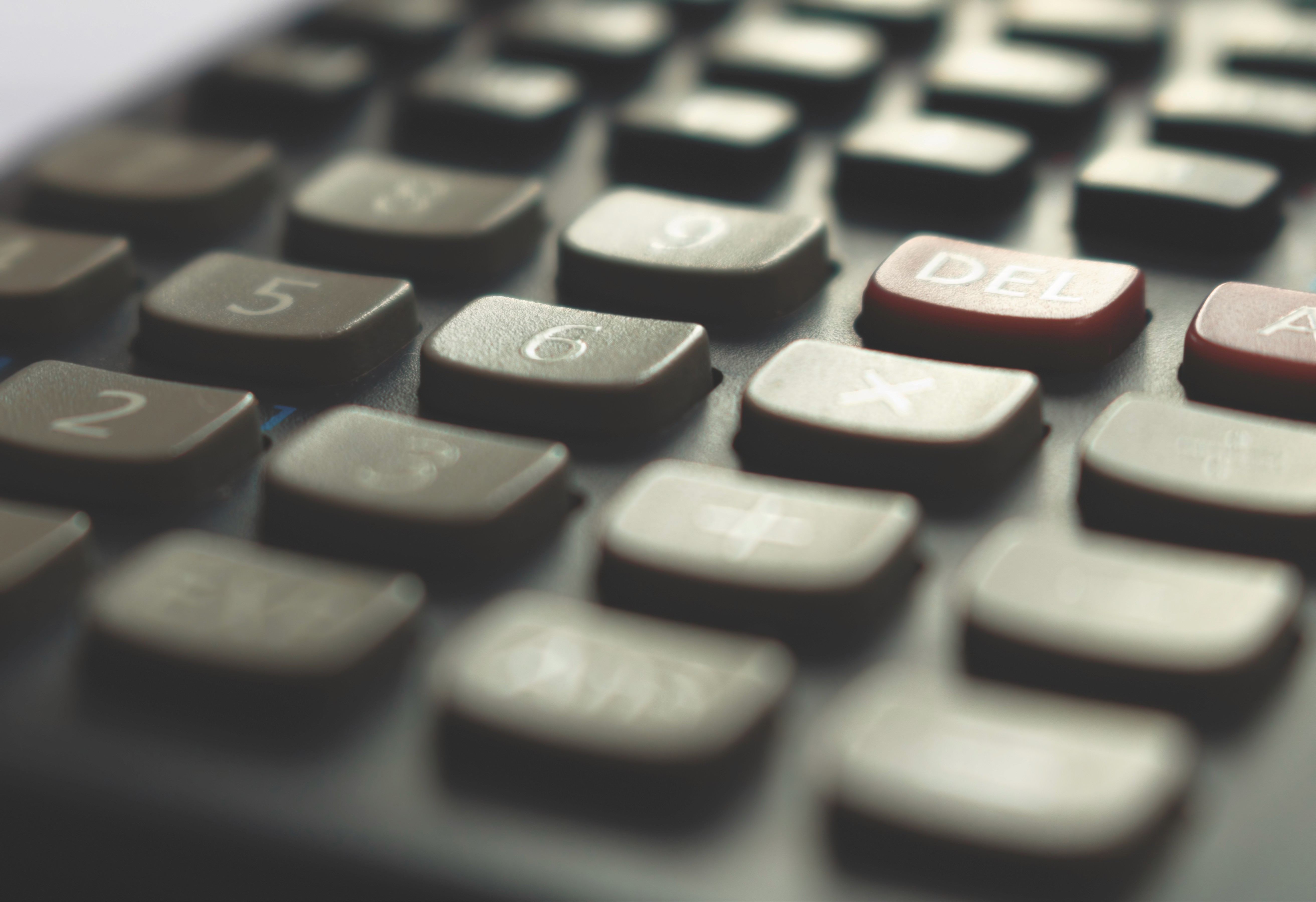 Modern red brick apartment or office building viewed from below against a blue sky, showcasing its geometric architecture with evenly spaced windows and balconies.