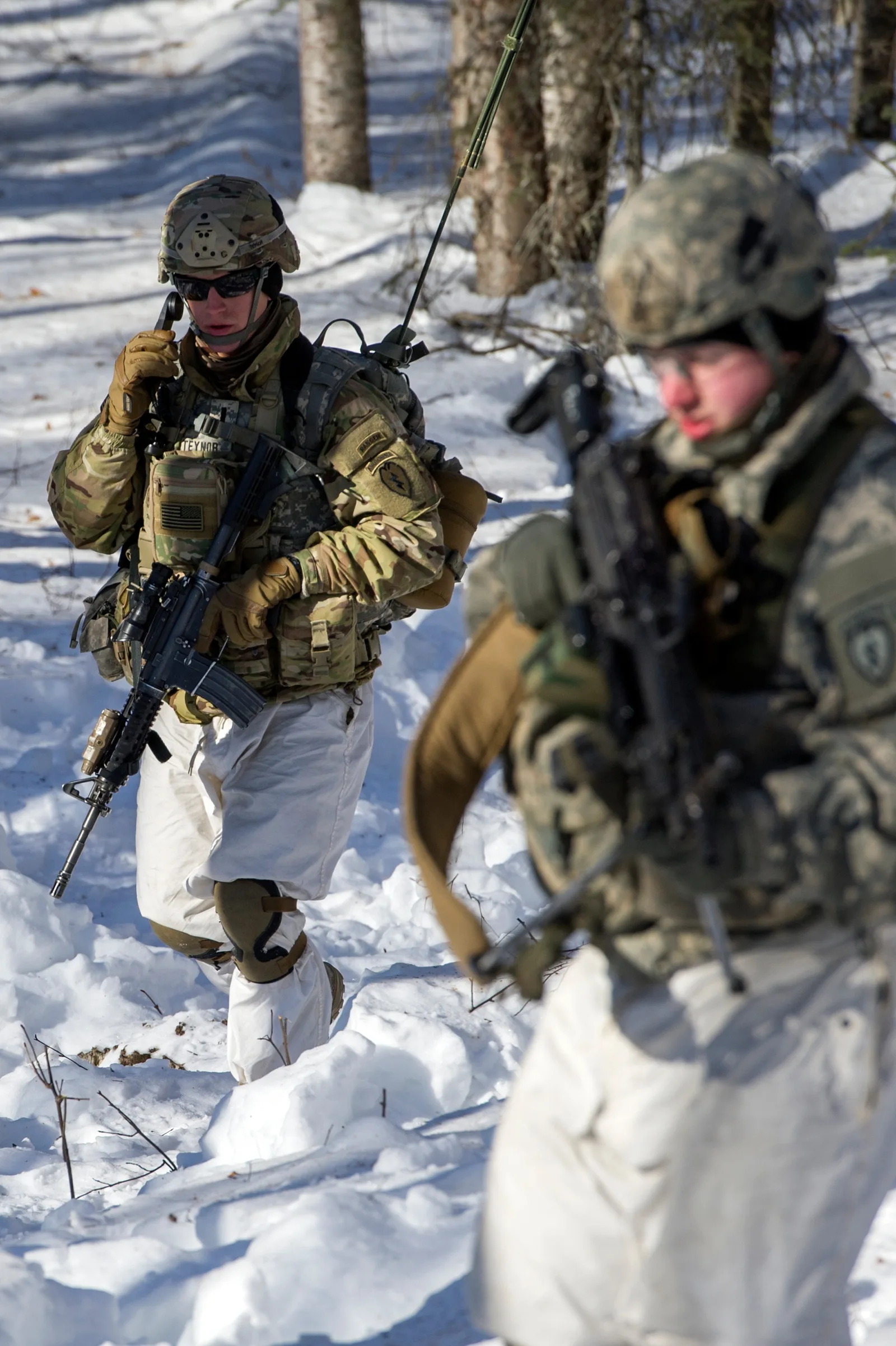 A platoon leader on the radio with his RTO behind him during a live-fire exercise on the Infantry Platoon Battle Course at Joint Base Elmendorf-Richardson, Alaska