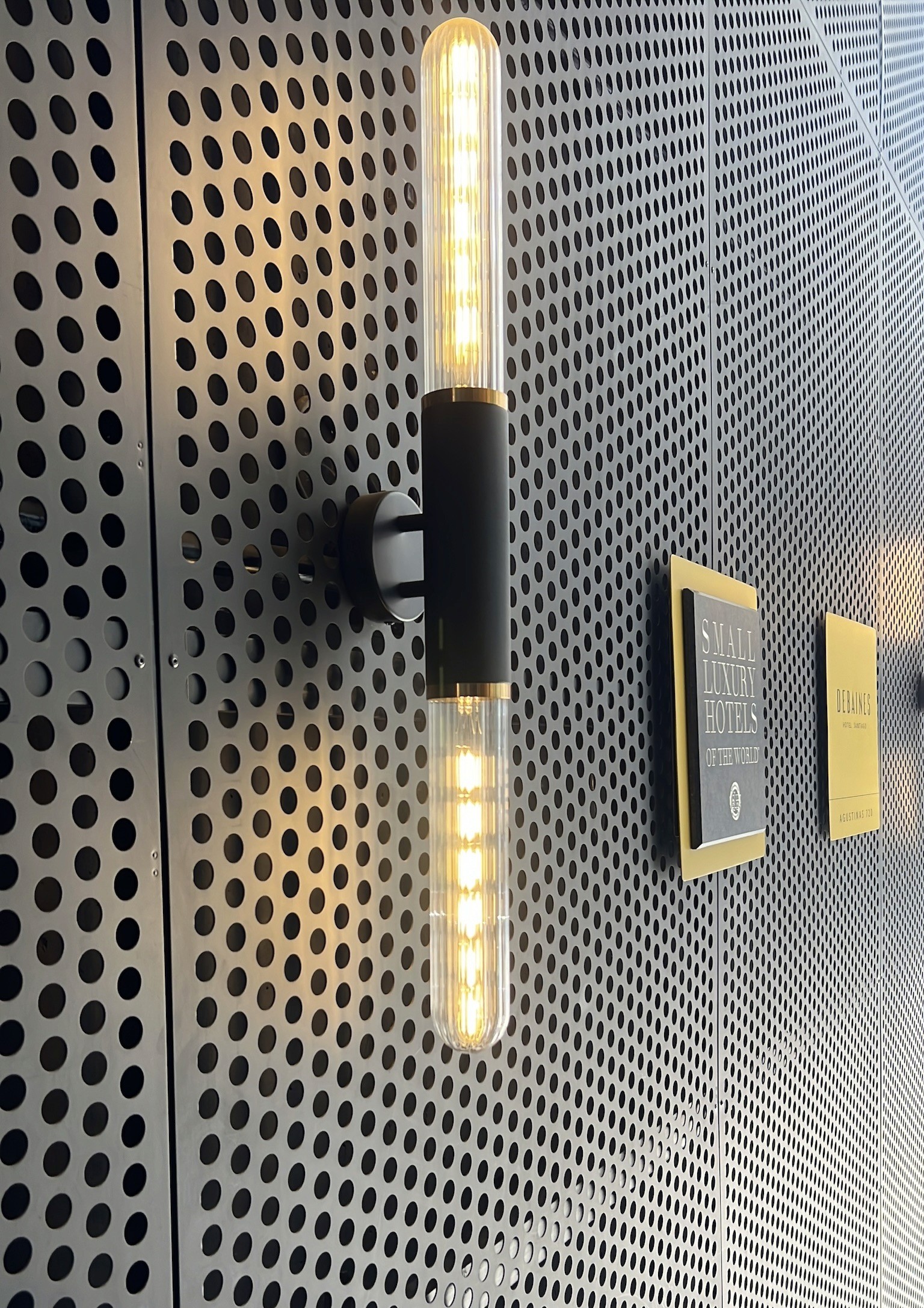 Abstract image of a wall featuring modern light fixtures and textured gray panels.