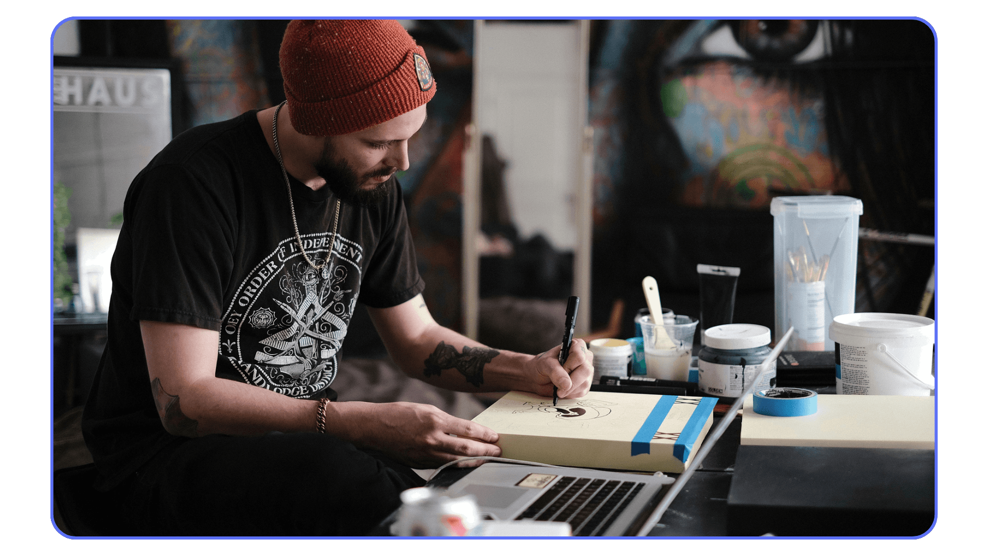 Artist sketching artwork by hand while using a laptop for creative reference