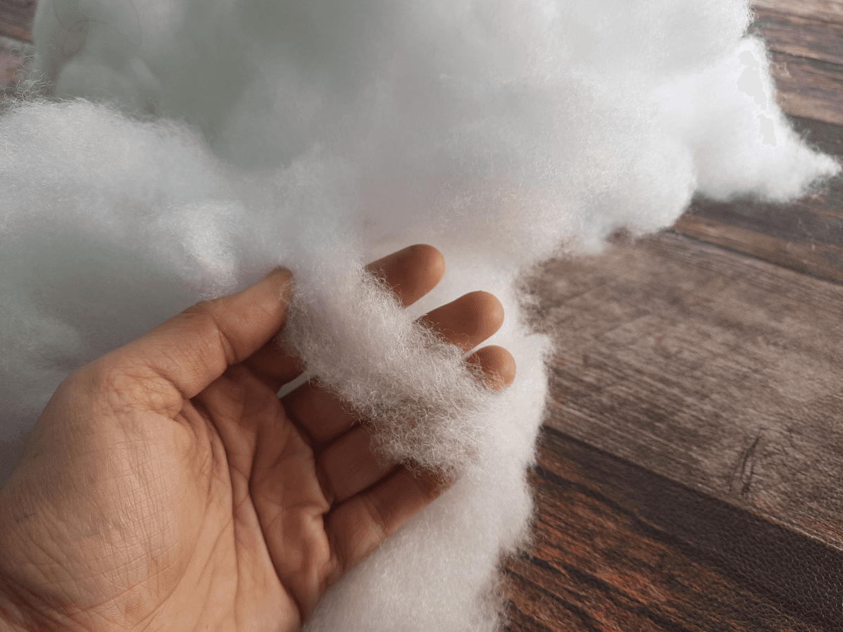 A hand holding a pile of white cotton
Description automatically generated