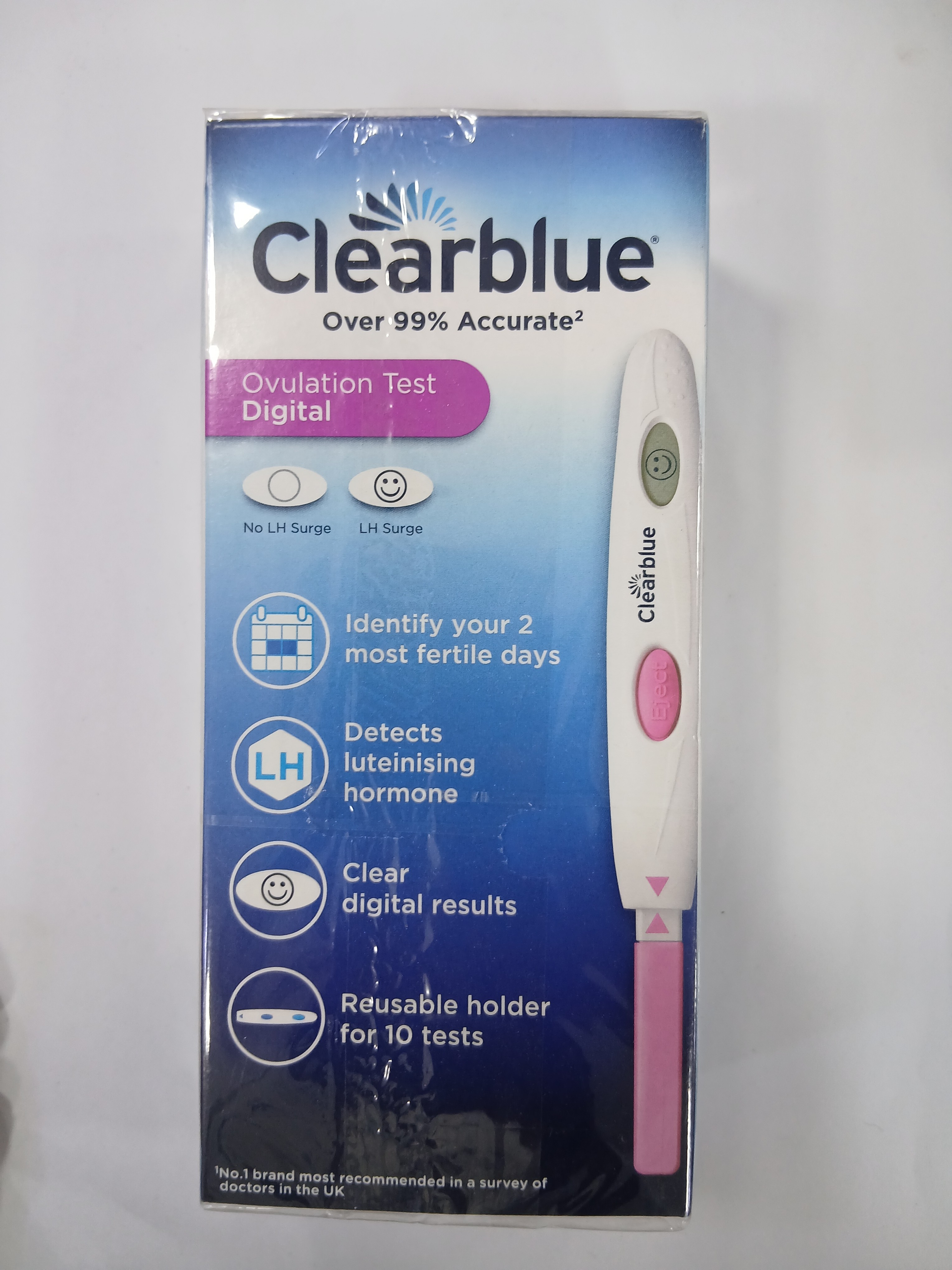 A white and blue digital ovulation test device with a reusable holder is displayed next to its white cardboard packaging featuring accuracy claims, icons for fertility detection, and clear digital results.