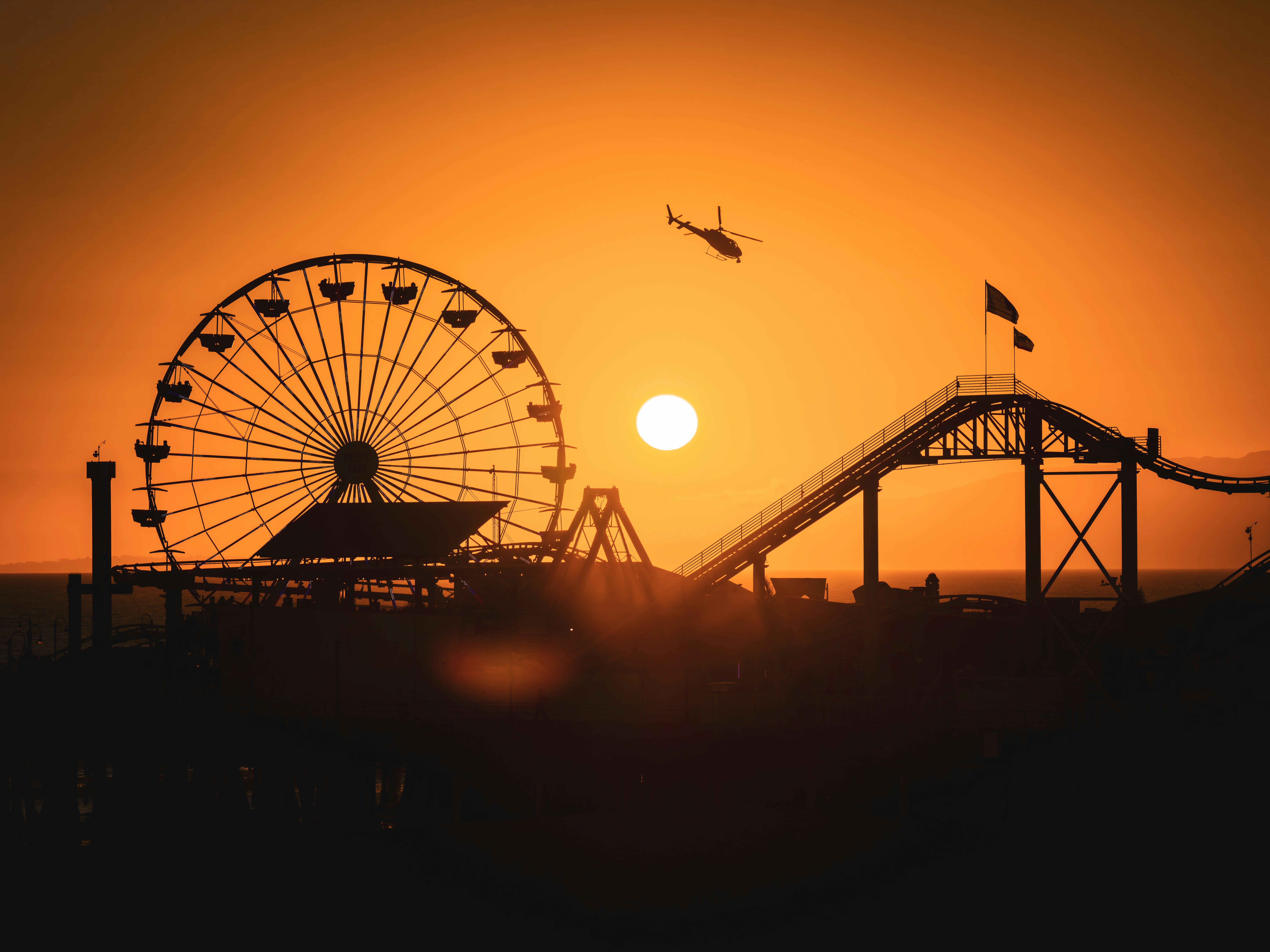 Amusement park rides silhouetted against a vibrant sunset.