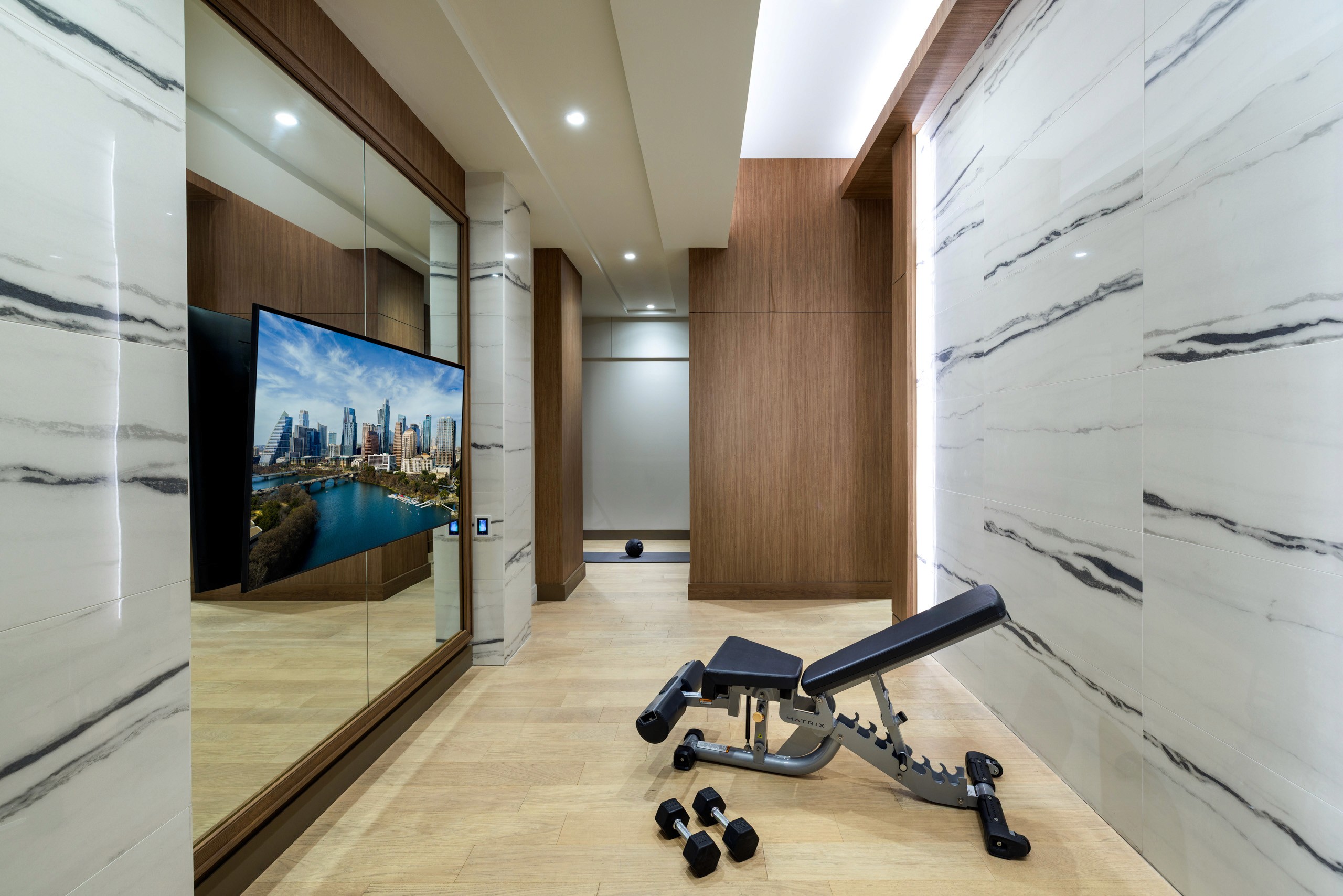 Weight bench and dumbbells, TV showing city skyline