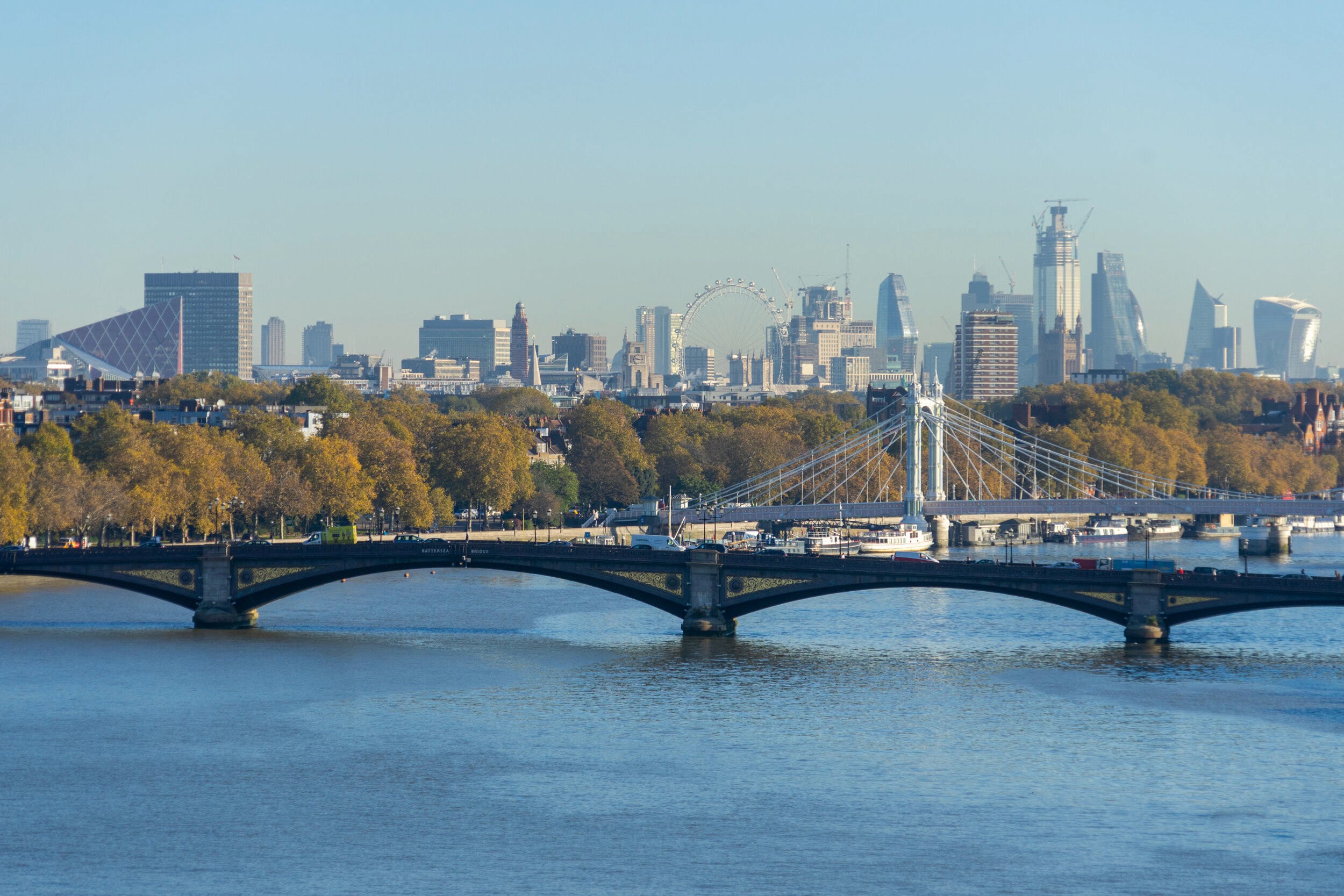 A scenic view of London’s Albert Bridge with the skyline in the background, featuring the London Eye and modern skyscrapers.