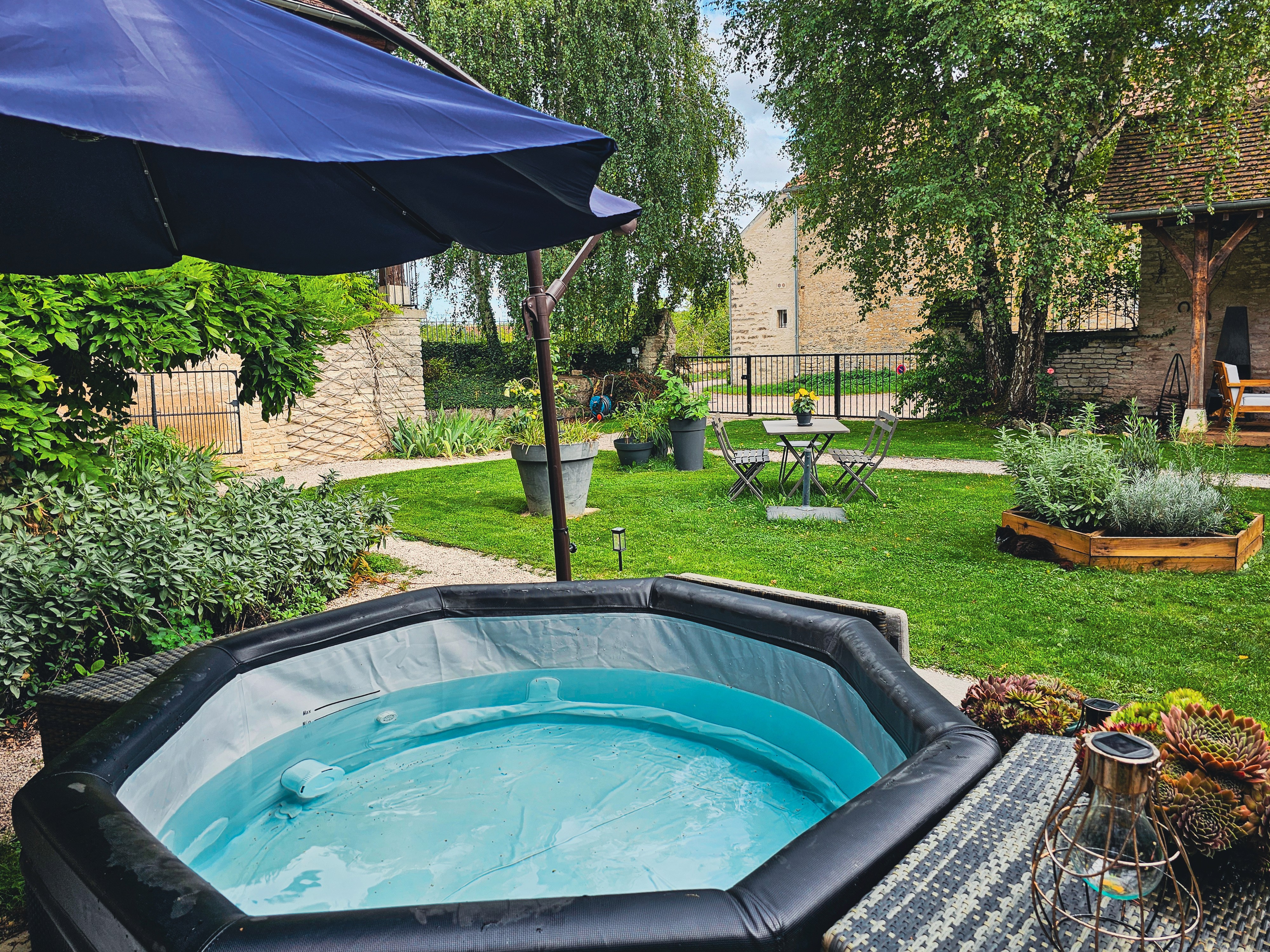 Jacuzzi exterieur sous parasol bleu avec jardin