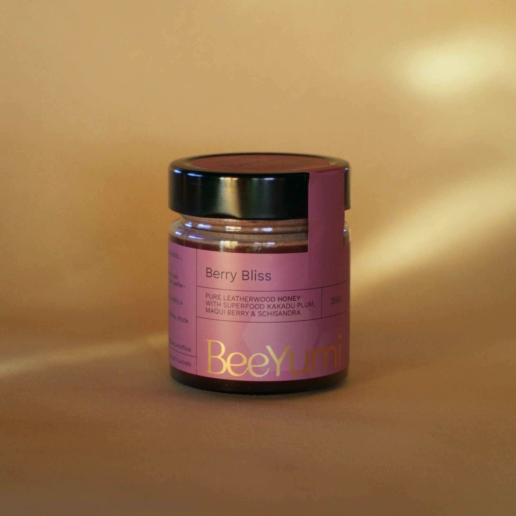 Jar of BeeYum Berry Bliss honey on a beige background