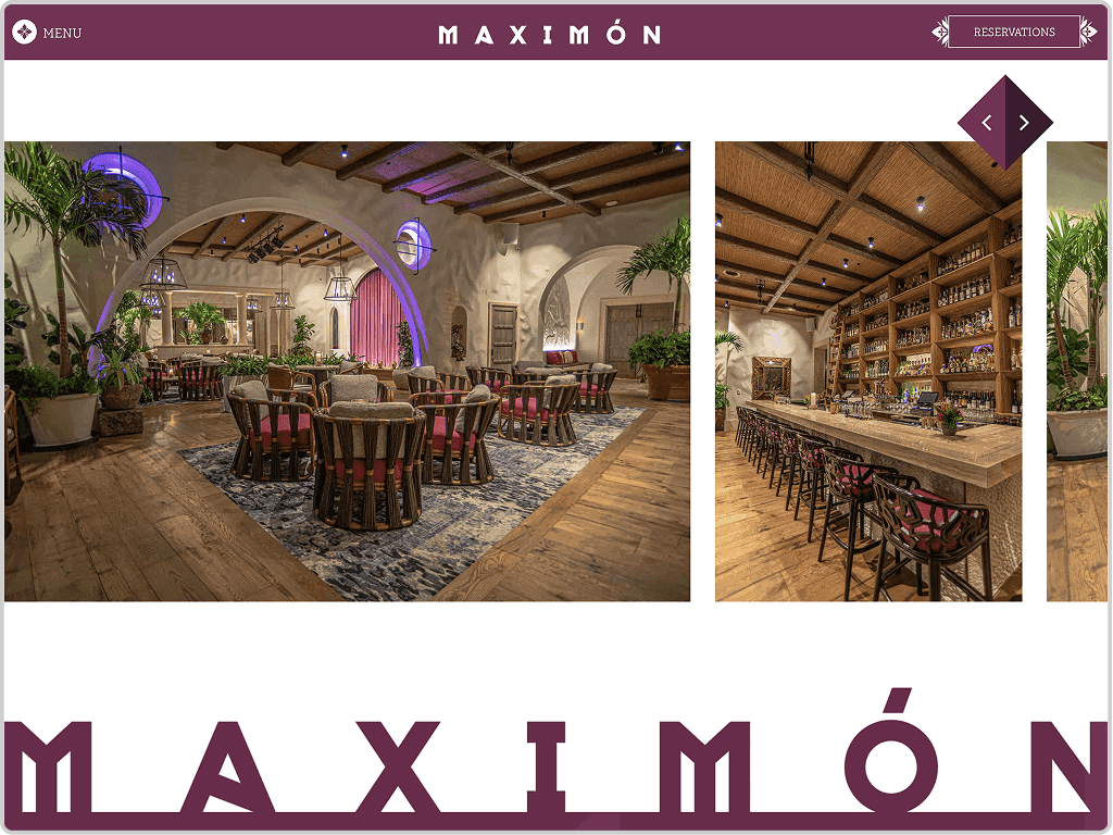 Interior of Maximon restaurant featuring a dining area with wooden tables and chairs, a blue rug, arched doorways, and a long bar with shelves of bottles.