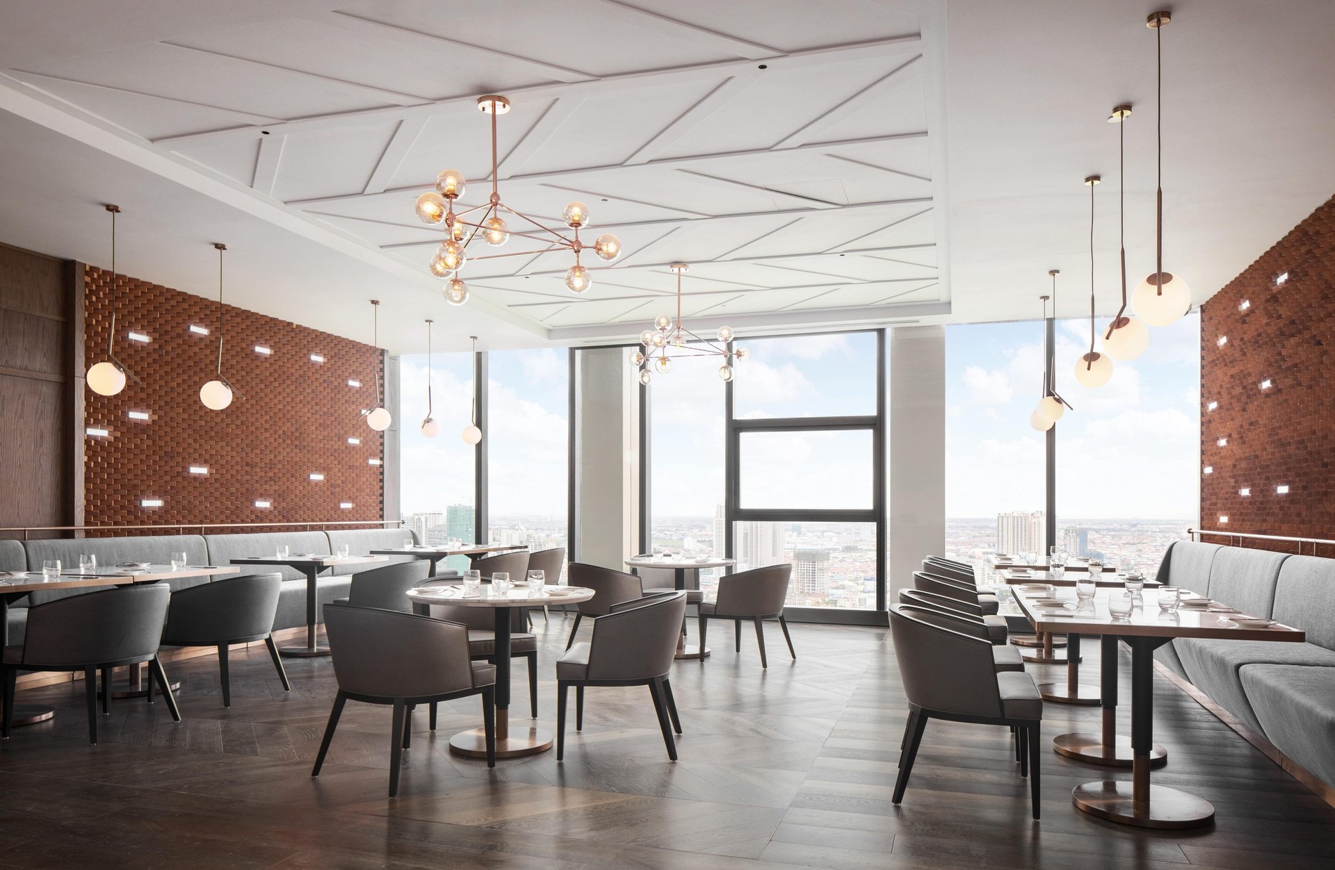 Luxury restaurant seating area with geometric wood paneling, designer lighting fixtures, and polished dark flooring.