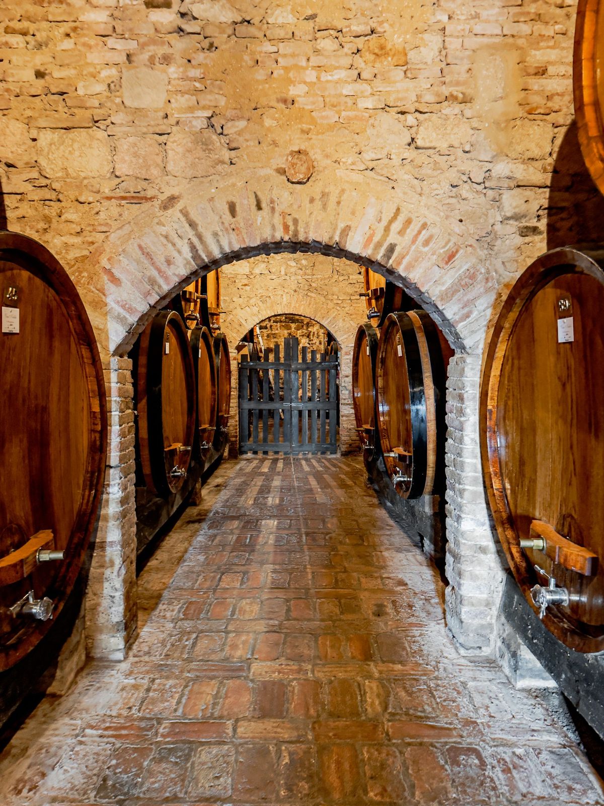 Large oak wine barrels aging Vino Nobile di Montepulciano in an underground tuff cellar