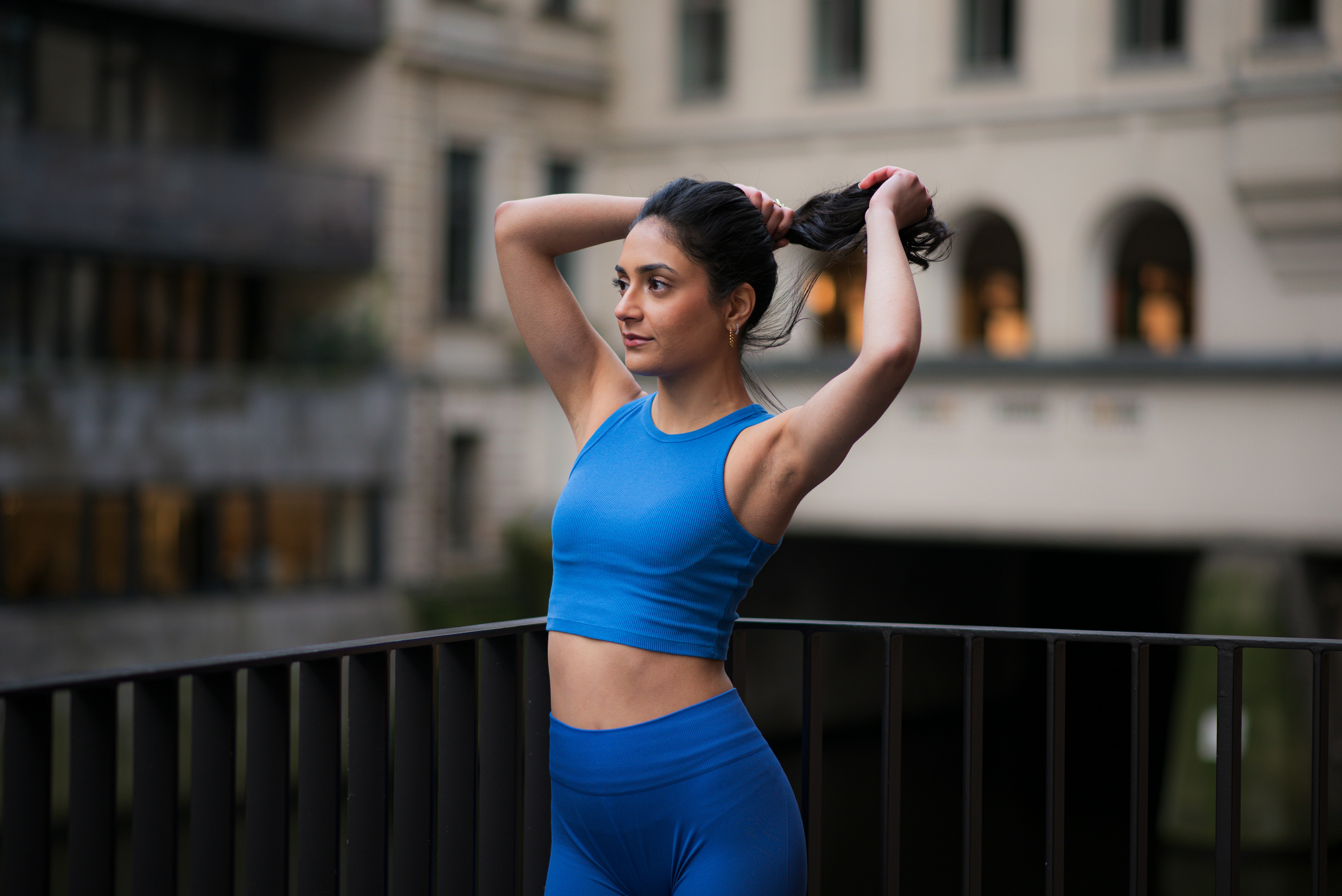Woman in workout gear pulls her hair back.