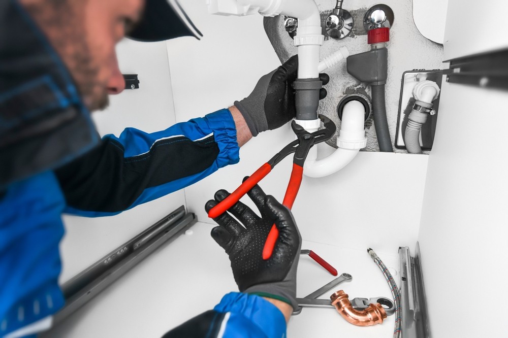 An emergency plumber fixing a leaky pipe in a bathroom