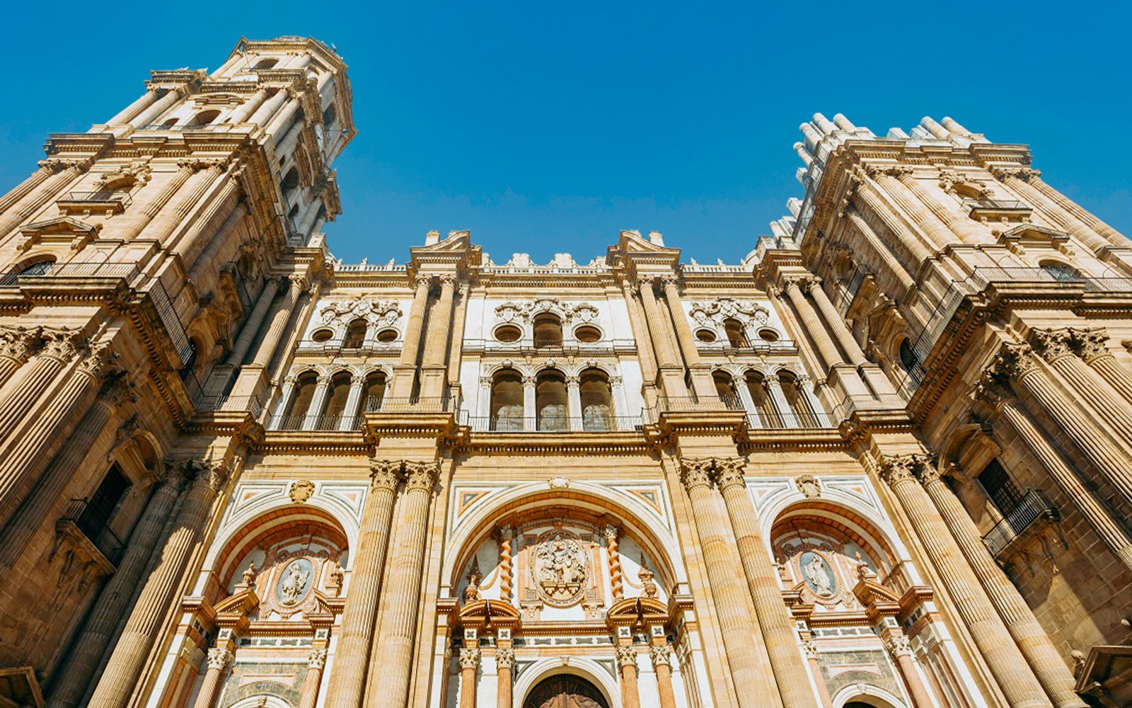 Facciata della Cattedrale di Málaga con dettagli architettonici sotto un cielo azzurro limpido.
