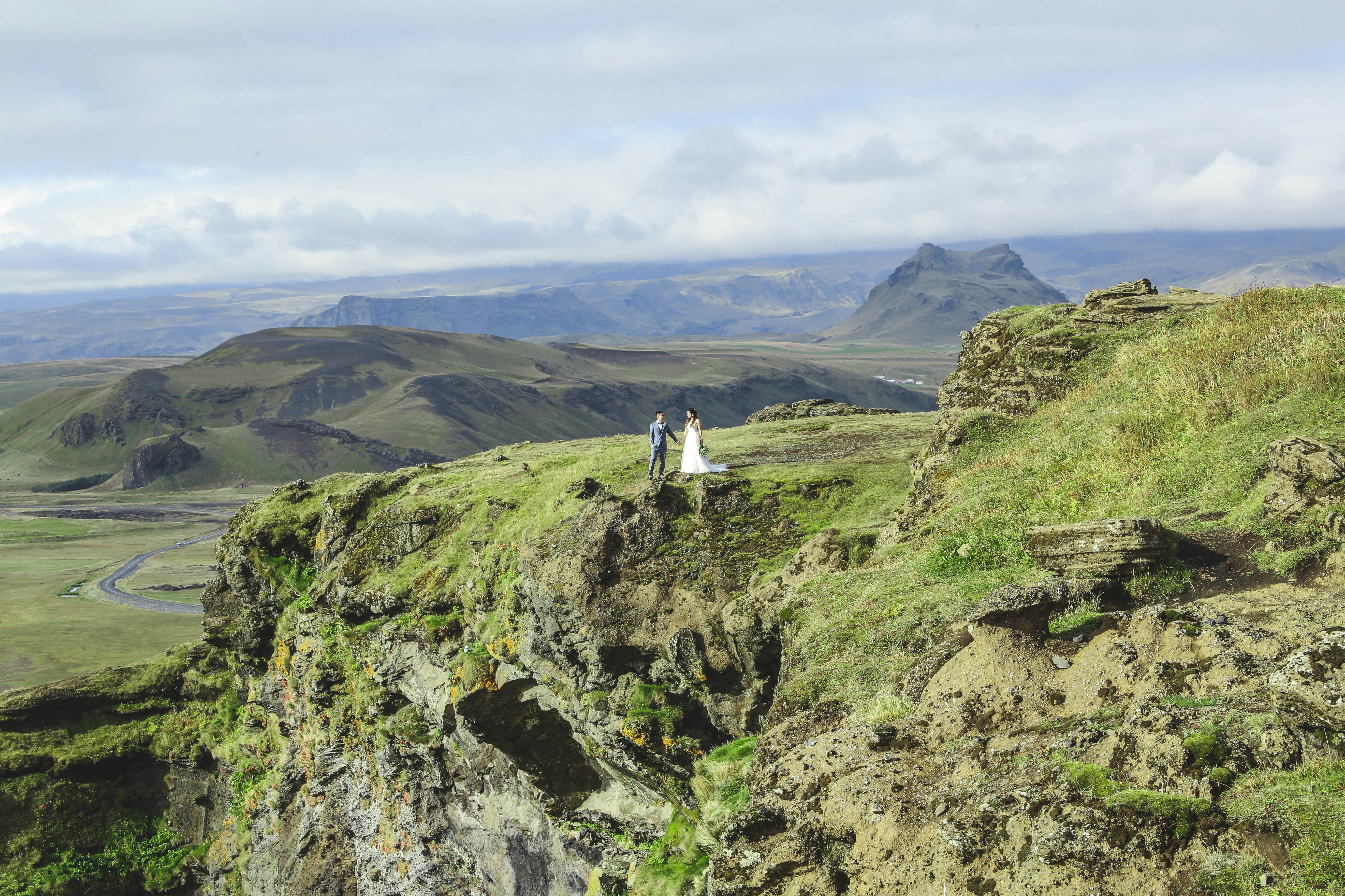 Bride and groom posing on a mountain summit in Iceland.