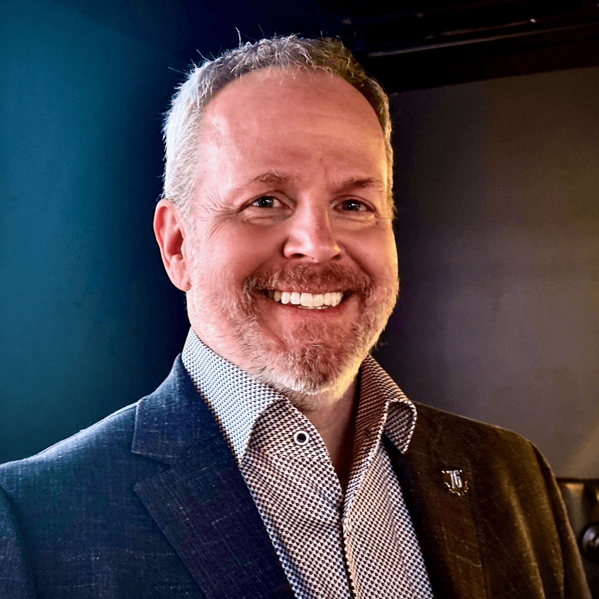 Brad Williams smiling in a blazer during a professional portrait.