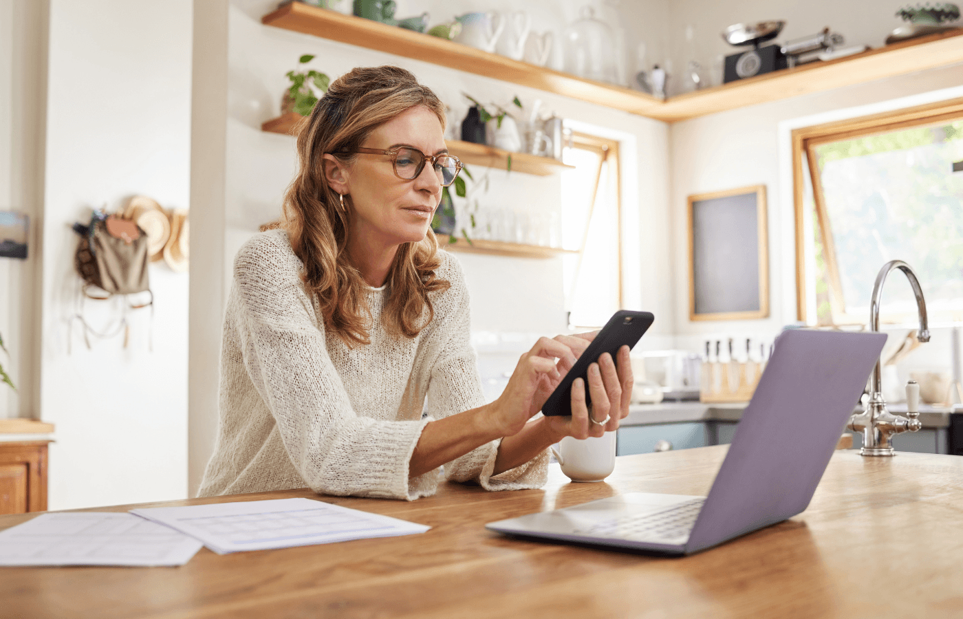 woman with phone, computer and paper documents