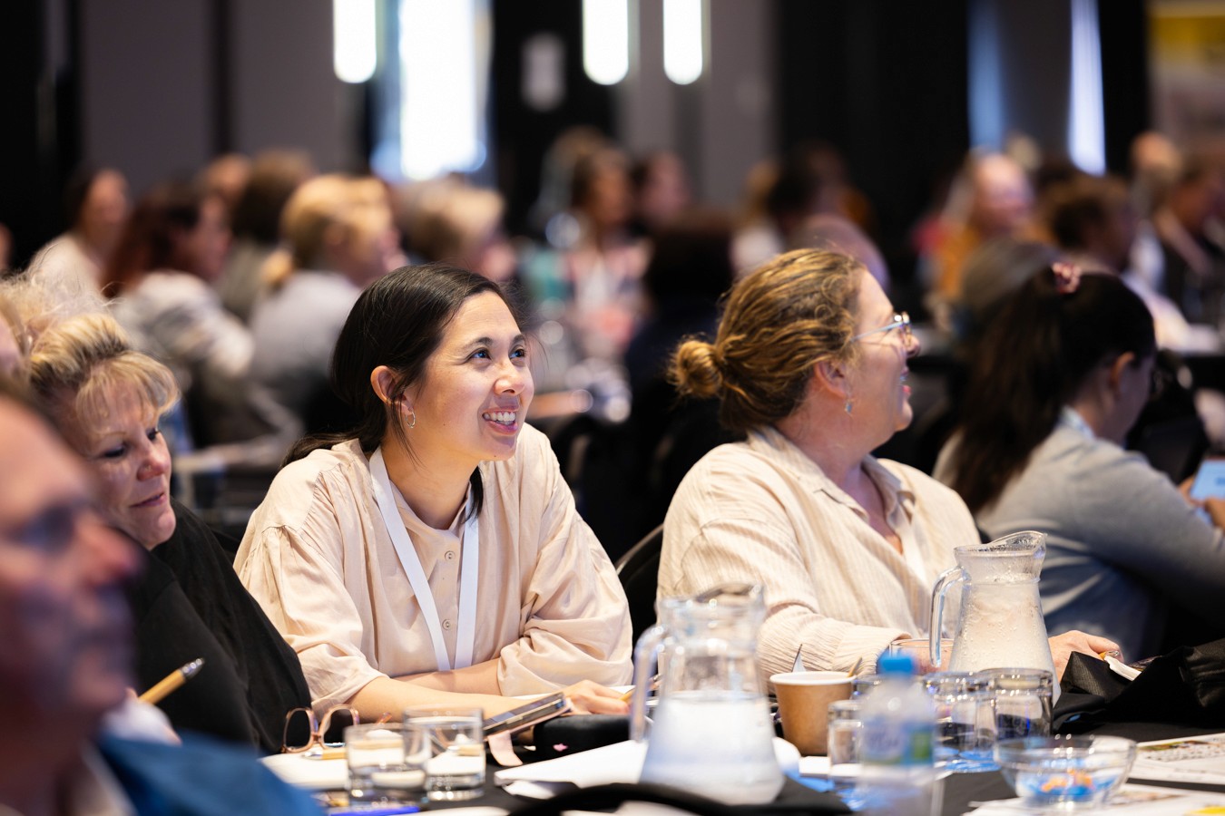 Woman smiling up at speaker from conference table