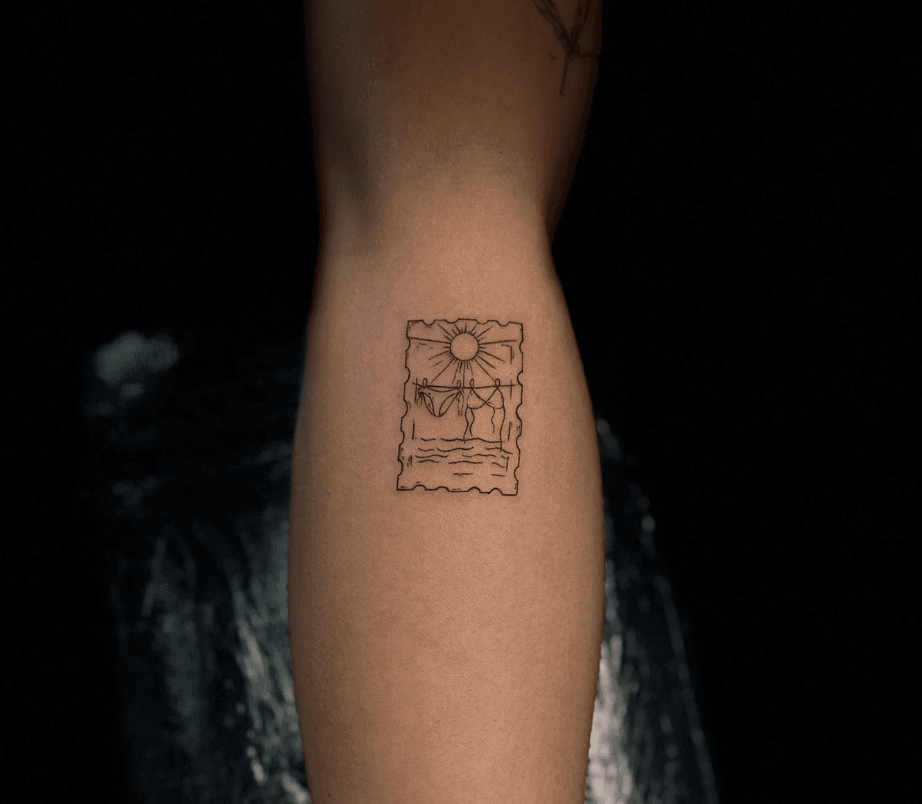 Whimsical minimalist tattoo featuring a curious cat behind a wineglass, accompanied by detailed moon phases and symbolic text "sun will rise" on the inner arm. Designed by Jai at Bloodworks Tattoo Studio, Auckland.