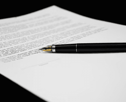 Fountain pen resting on a printed legal document or contract.
