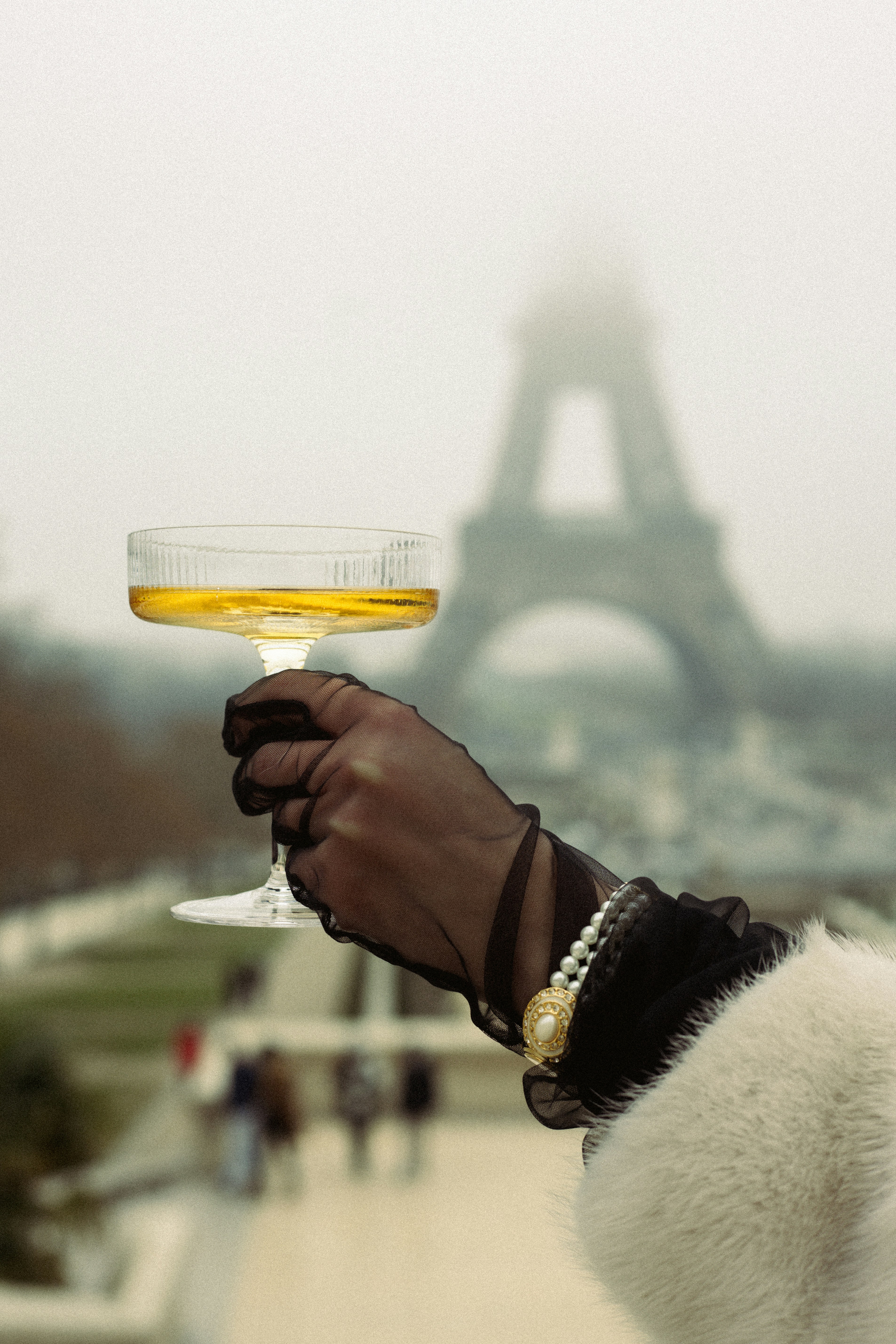 A person holding a wine glass in front of the eiffel tower