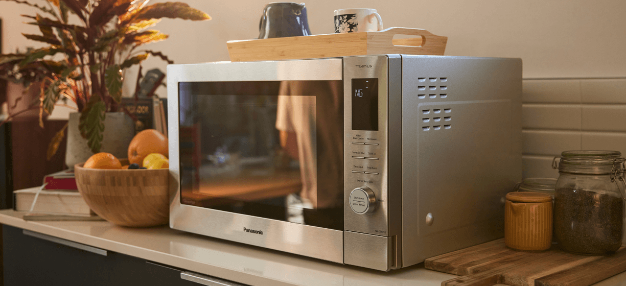 Panasonic 4 in 1 multi oven sits on a kitchen counter with a bowl of fruit and a wooden tray on top