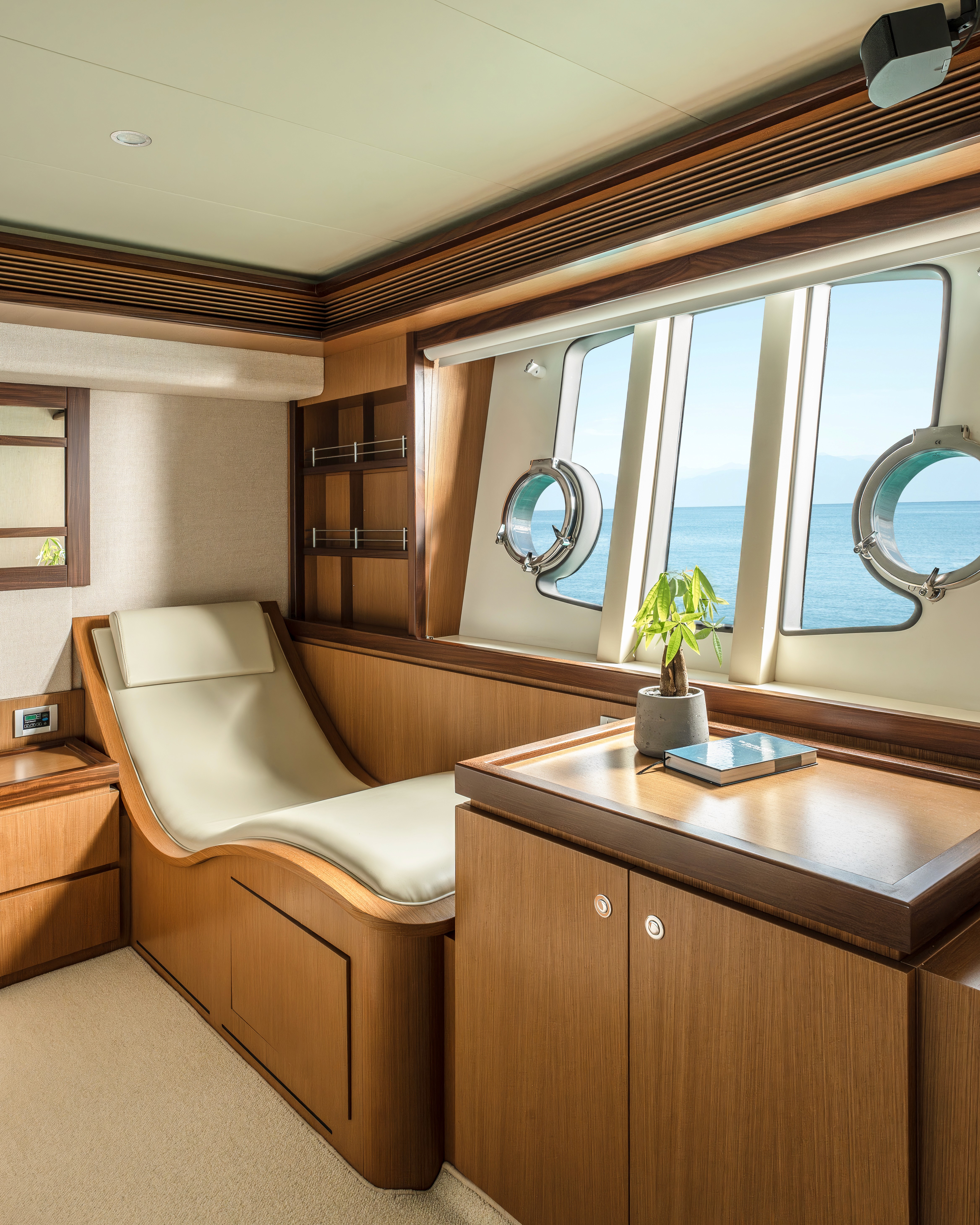 Luxurious interior salon of Ferretti 63 Escape yacht featuring cream leather seating, wood finishes, and panoramic windows overlooking the sea.