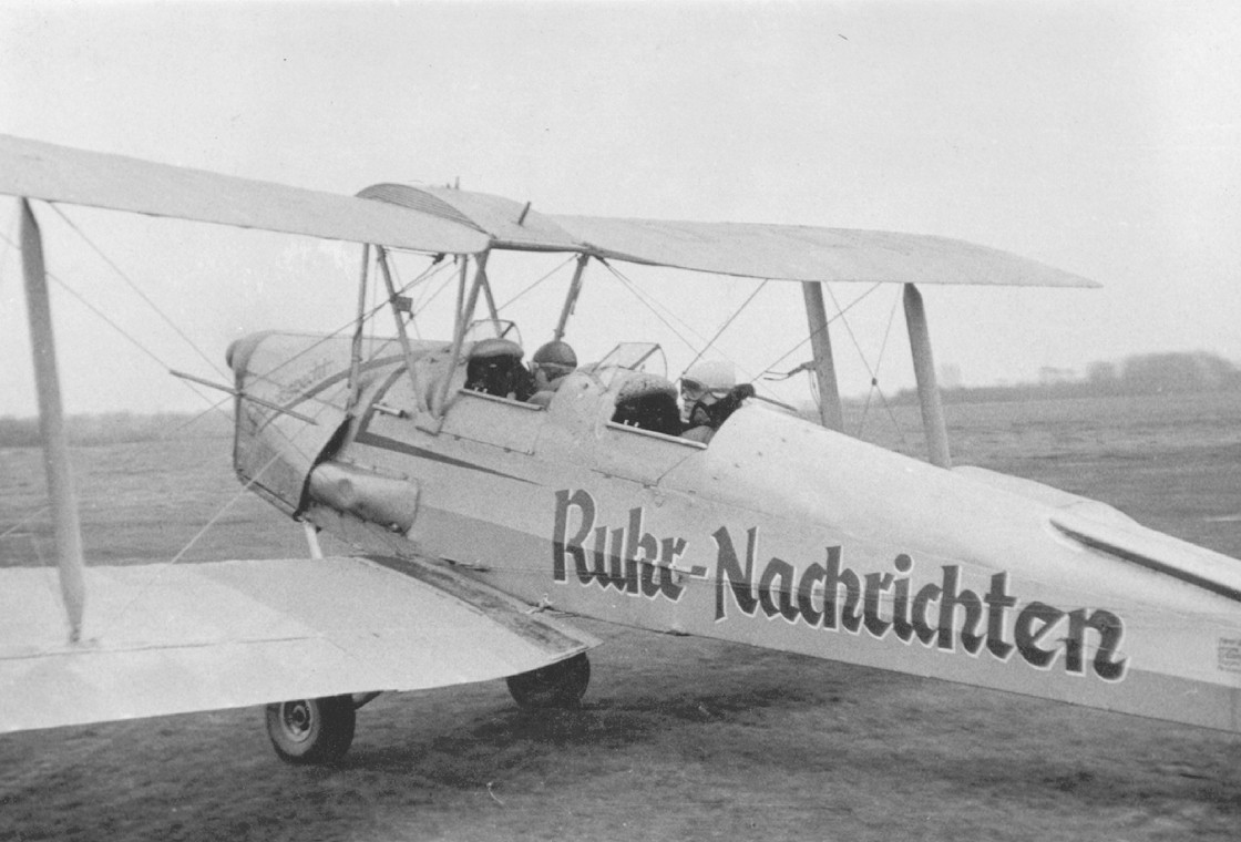 Kleines Propellerflugzeug mit Ruhr Nachrichten Schriftzug auf Graspiste