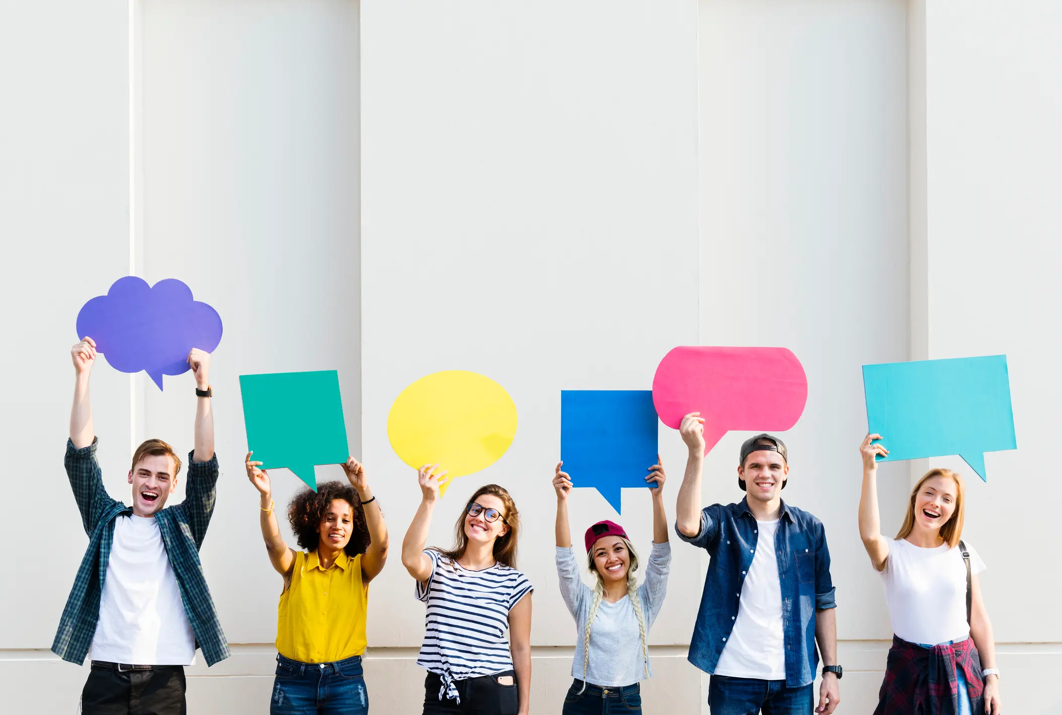 Young diverse group holding colourful speech bubbles representing freedom of expression in teams