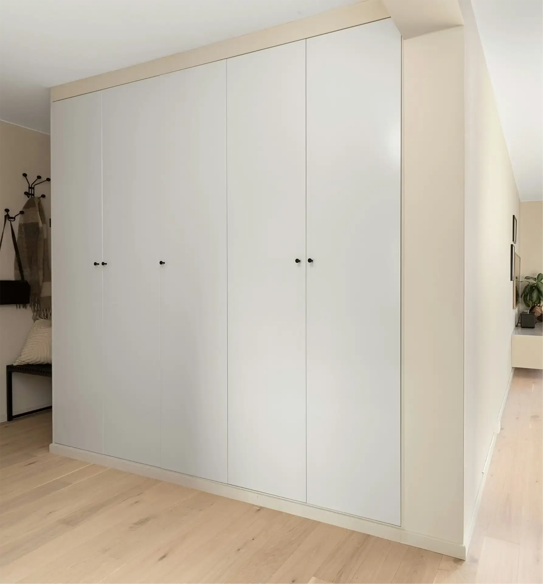 Pojemna biała szafa wnękowa pod sufit o minimalistycznym wyglądzie, idealnie dopasowana do wnęki.