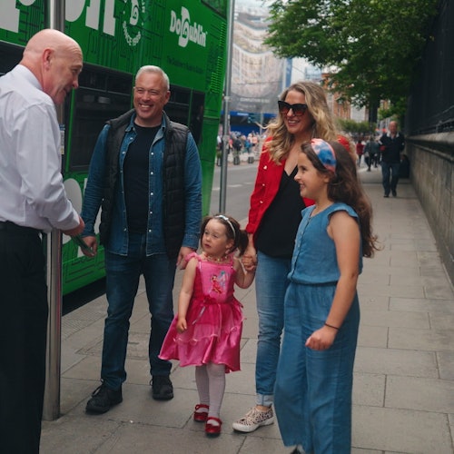 Family of four talking to a bus driver before getting on board