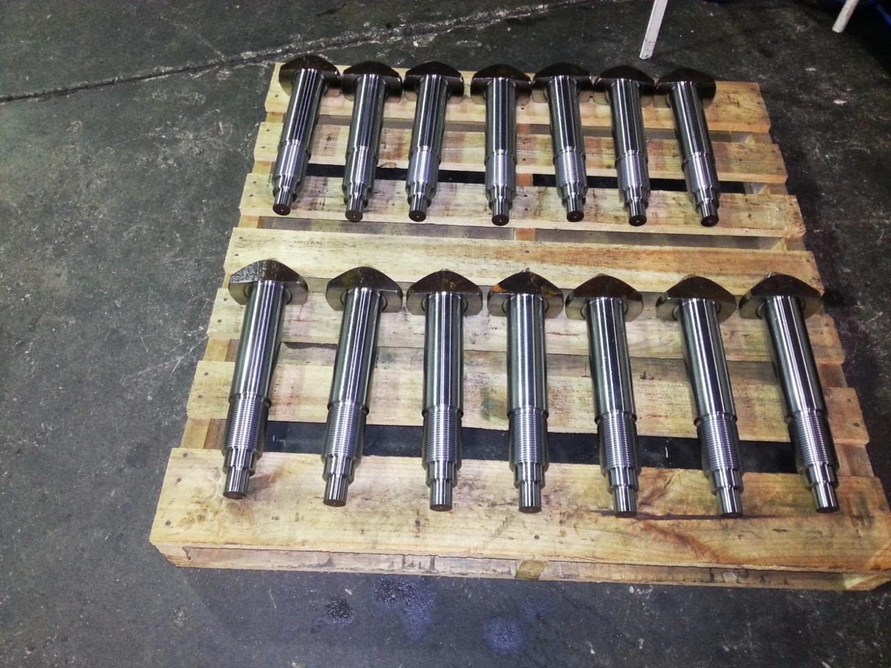 Finished precision-machined industrial steel shafts with threaded ends, neatly arranged on a wooden pallet.