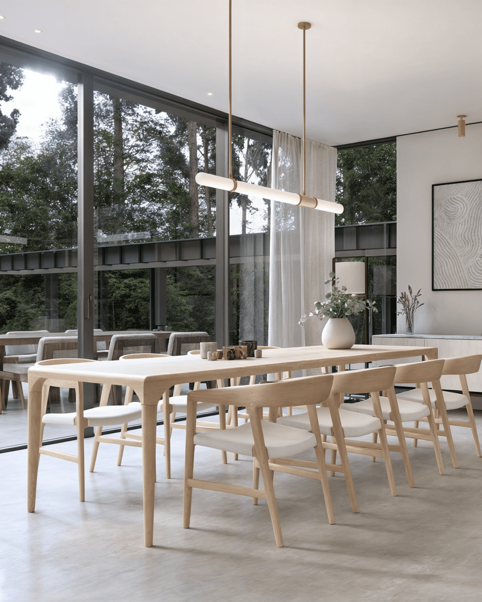 Moderne eetruimte met lichte houten tafel, minimalistische stoelen en hoge glasgevel met uitzicht op groen.