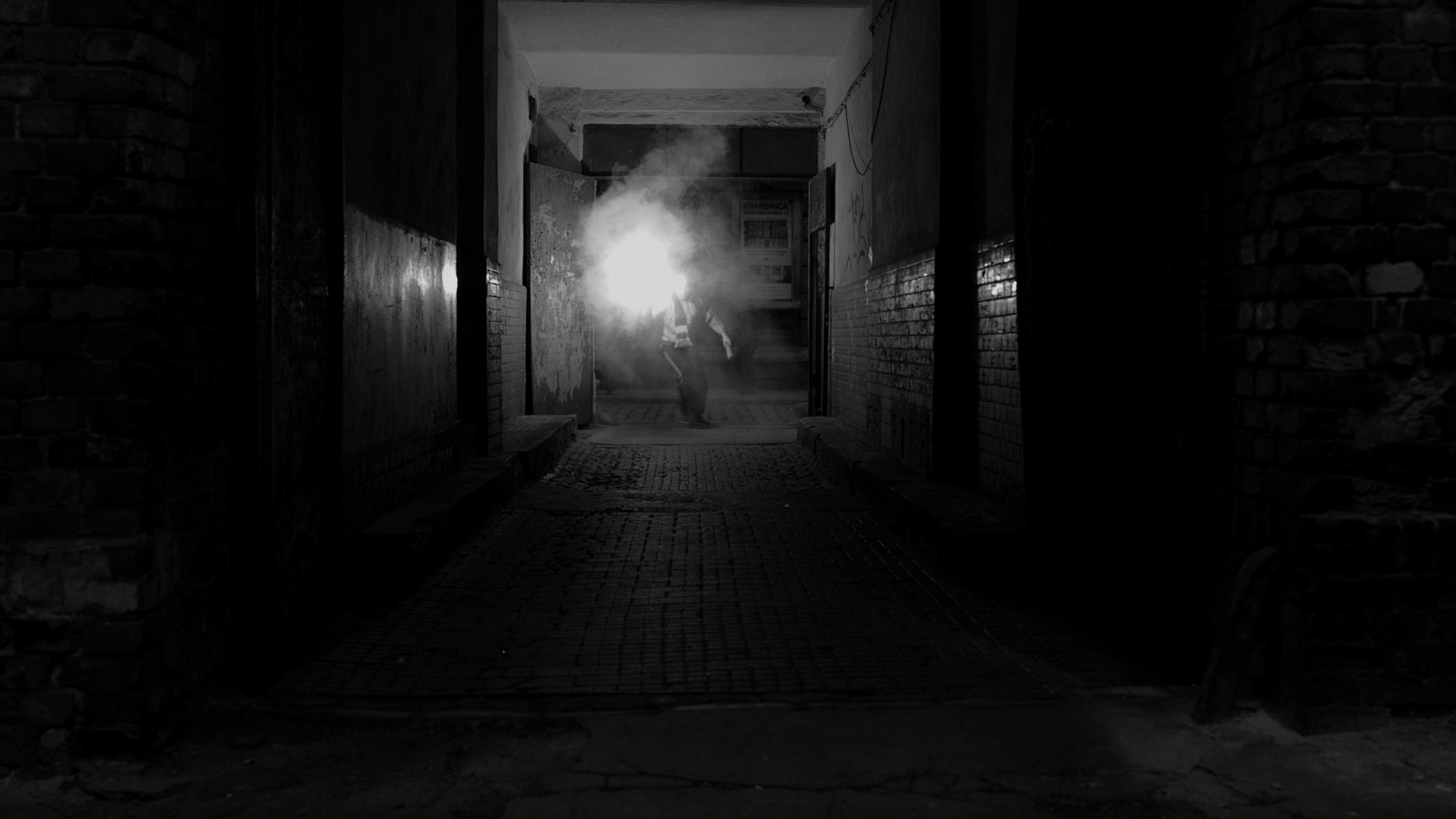 High contrast black and white shot of a dark tunnel silhouette with light at the end.