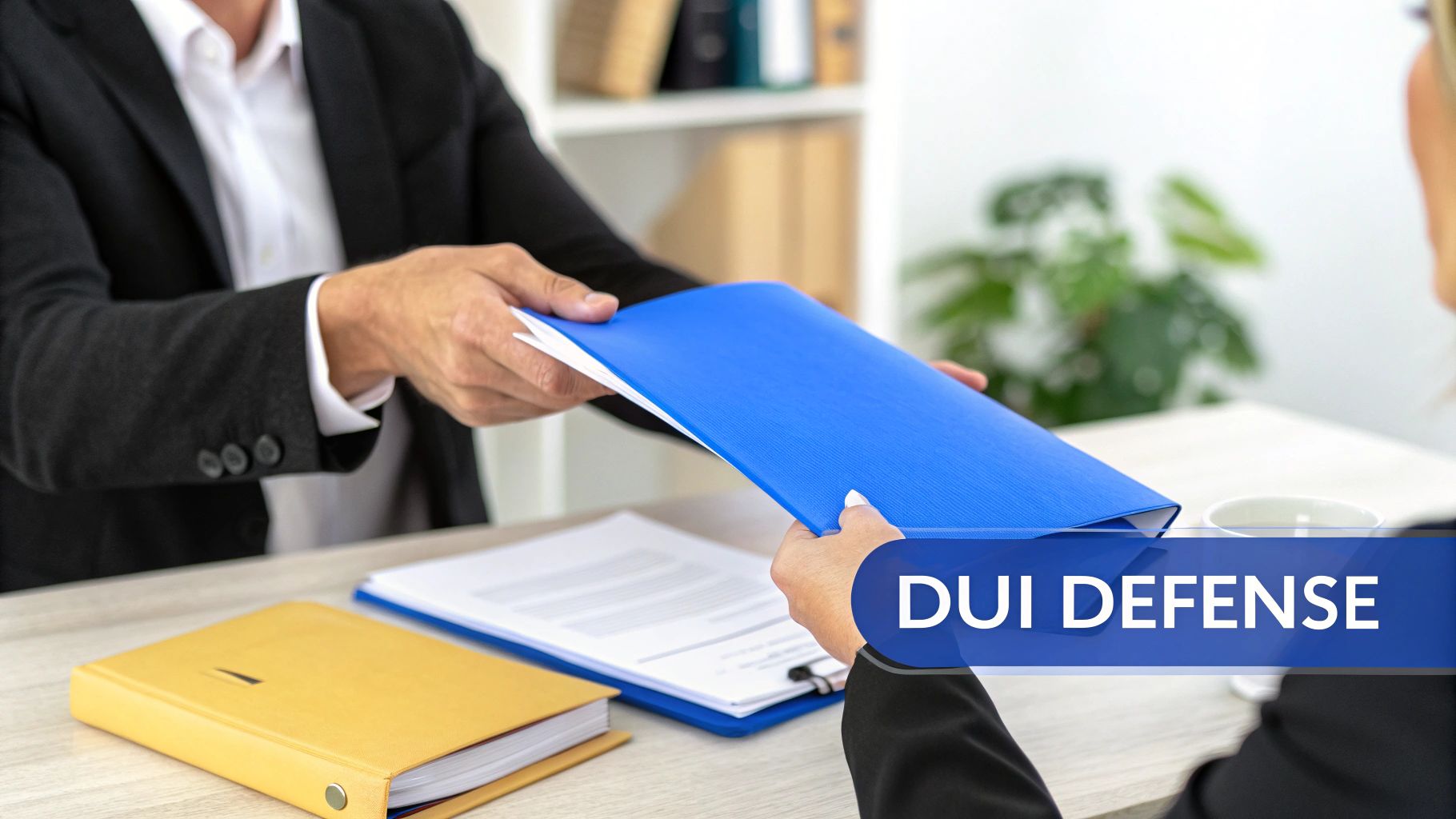 A lawyer hands a blue folder with DUI defense documents to a client during an office meeting.