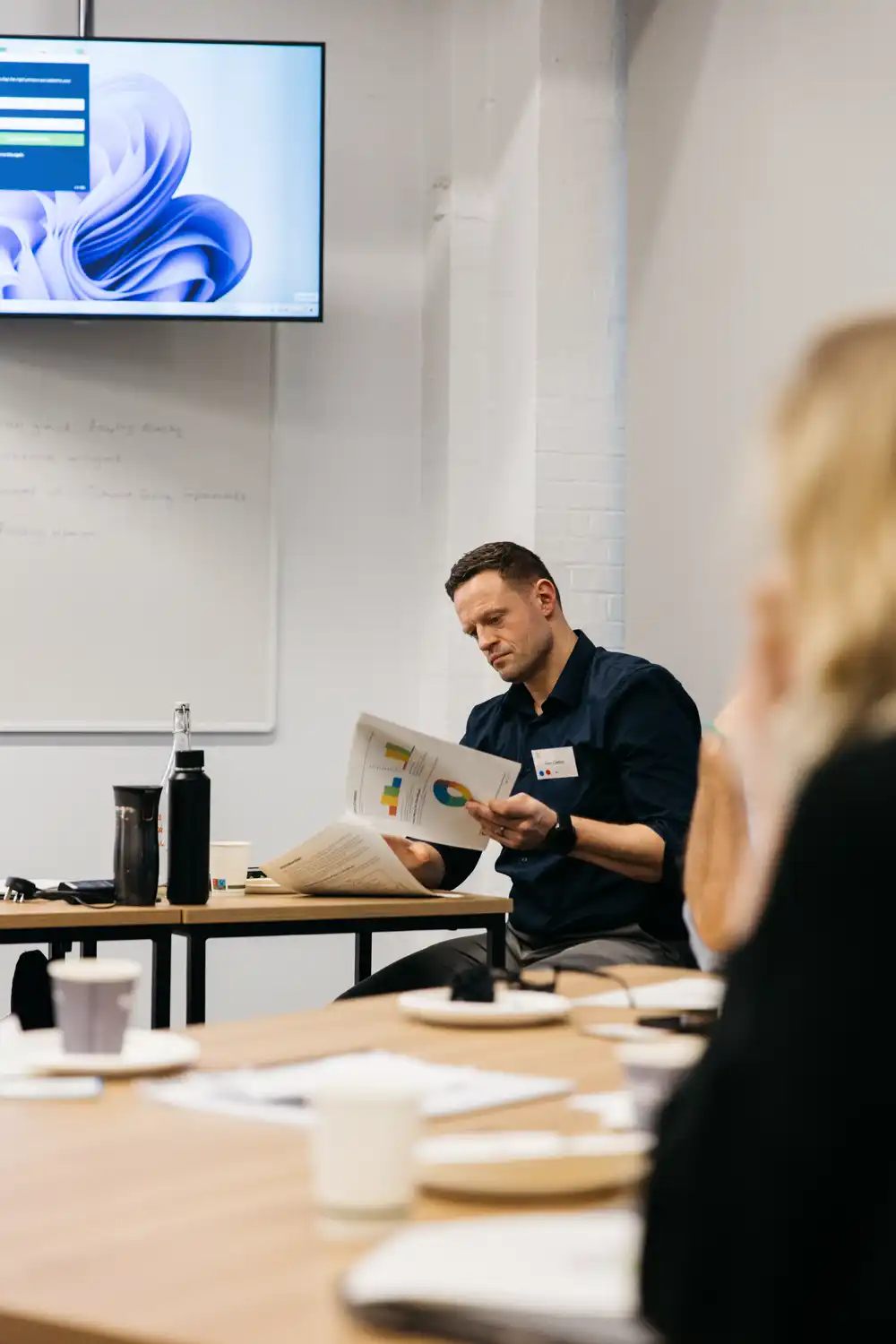 Person sitting in a classroom using an older model laptop.