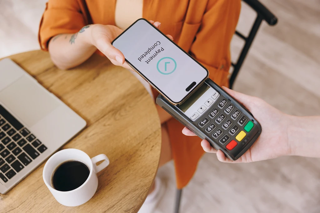 Female customer tapping her phone on a point of sale terminal