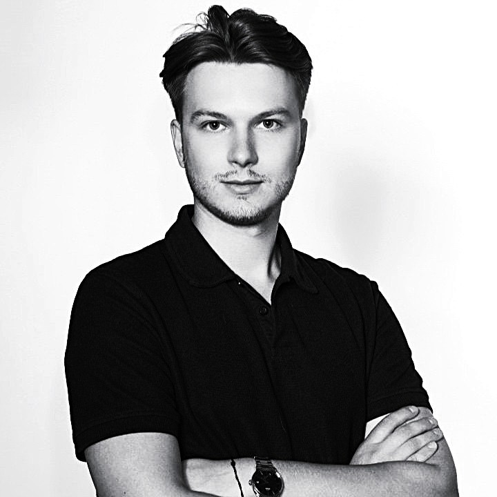 A man with glasses and a brown shirt, crossing his arms.