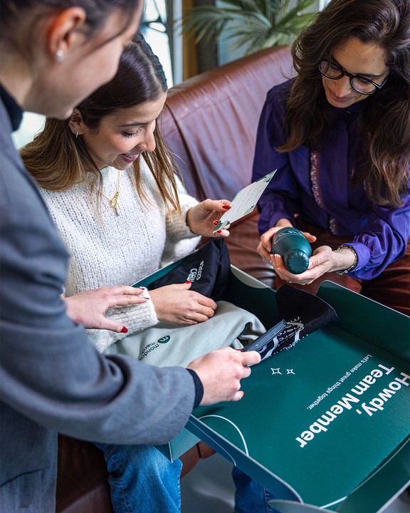 People examining a gift box with an insulated bottle and other items