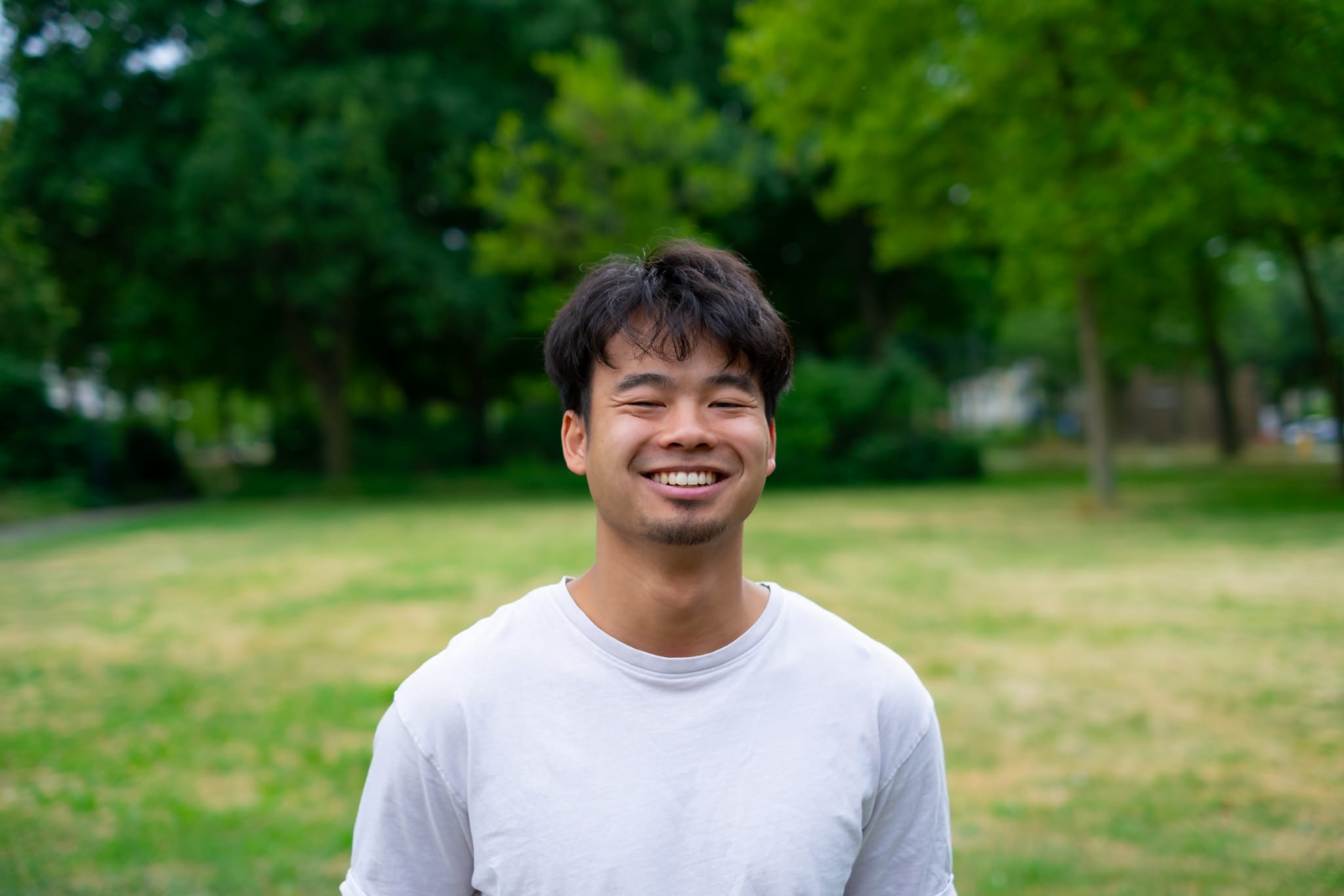 Quang, masseur van Sport Zen Massage, lachend buiten in het groen
