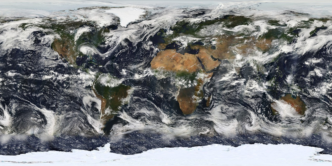 Zdjęcie satelitarne Ziemi przedstawiające globalne rozmieszczenie chmur i kontynentów z perspektywy przestrzeni kosmicznej.